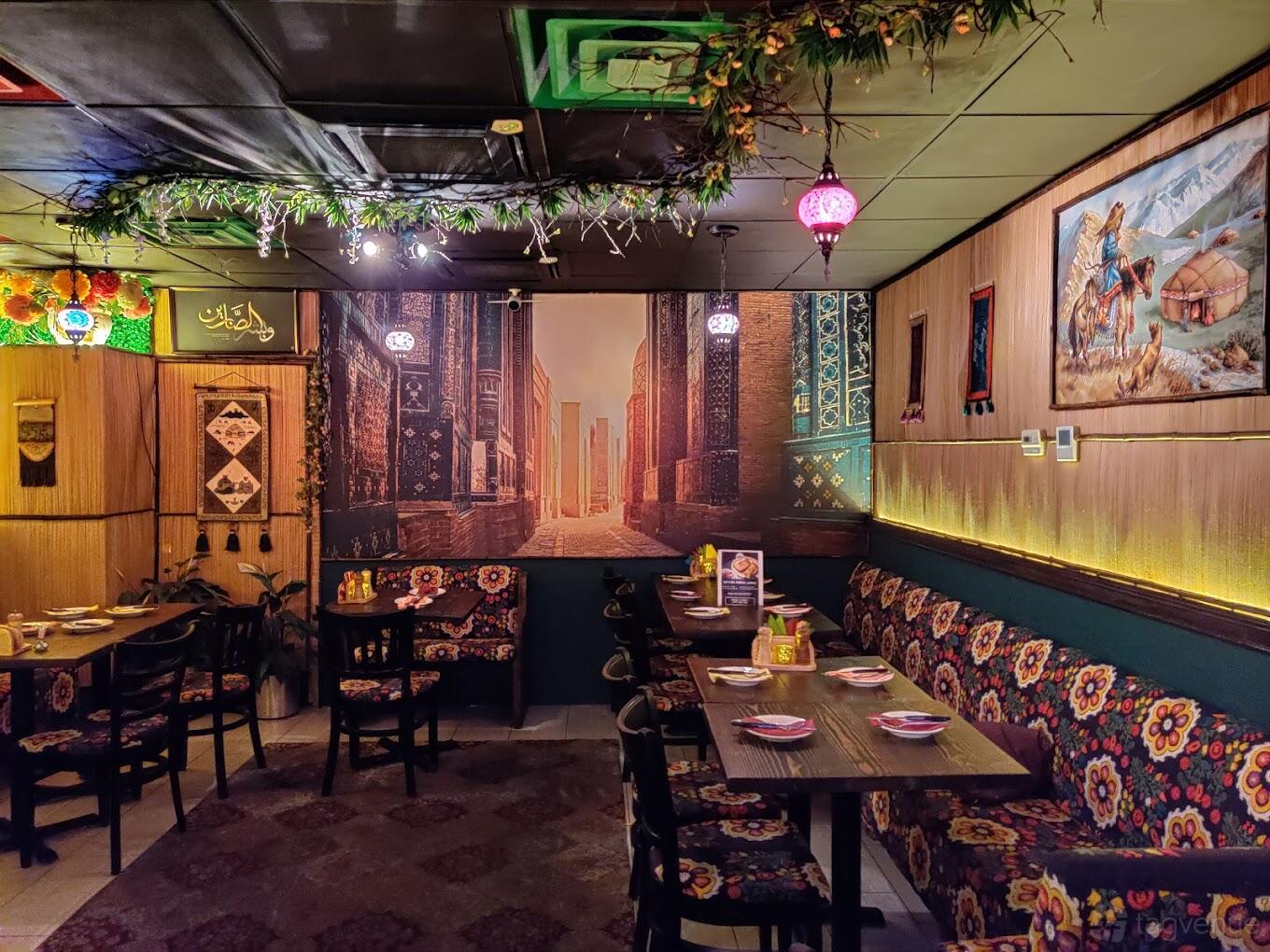 An event space in a restaurant with patterned banquette seating, hanging lanterns, and decorative wall art at Farida.