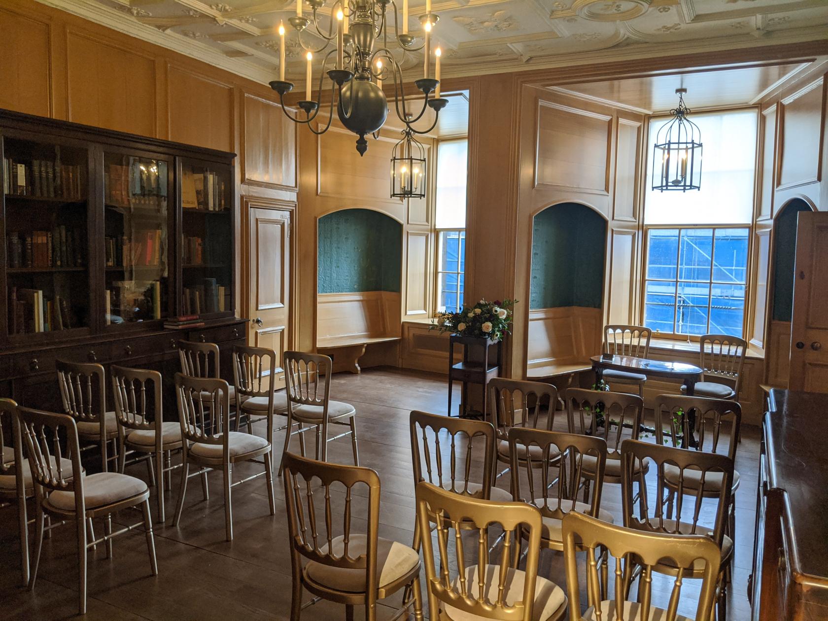A function room with wood paneling, built-in window seating, and rows of chairs at Riddle's Court.