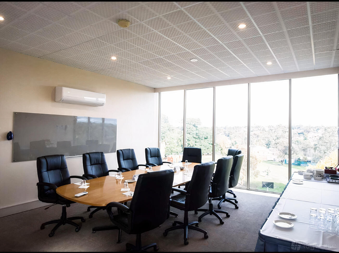 A boardroom with floor-to-ceiling windows, a long oval table, and high-back chairs at Best Western Airport Motel & Convention.