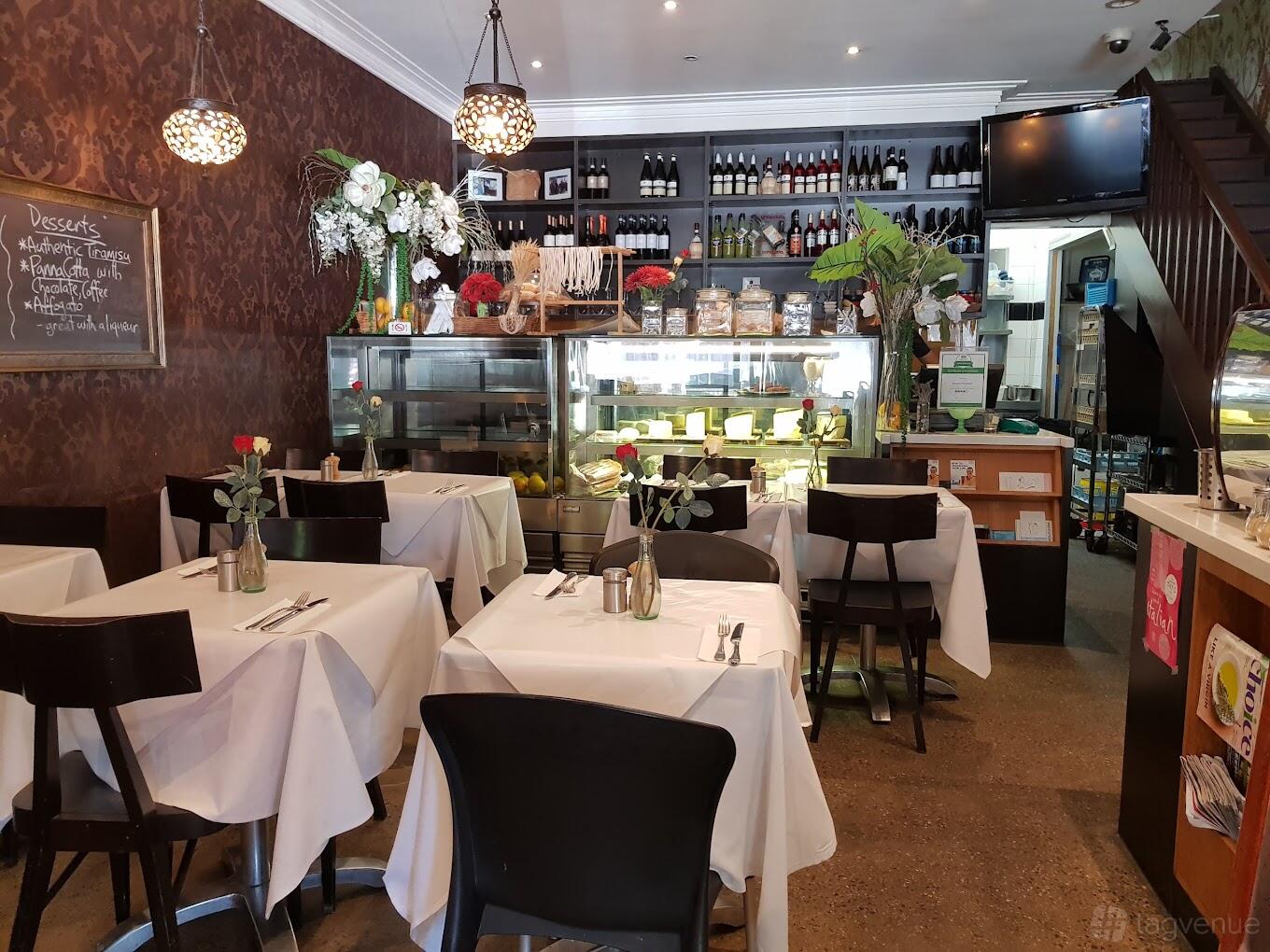 A restaurant with white tablecloths, floral centerpieces, and a display counter at Seasons Provedore.