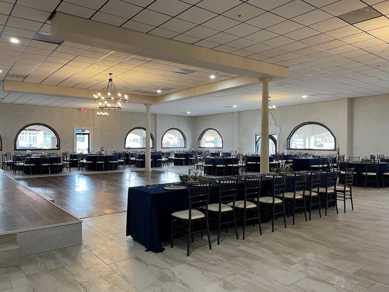 An event venue with arched windows, chandeliers, and banquet tables with navy linens at Casa Hacienda.
