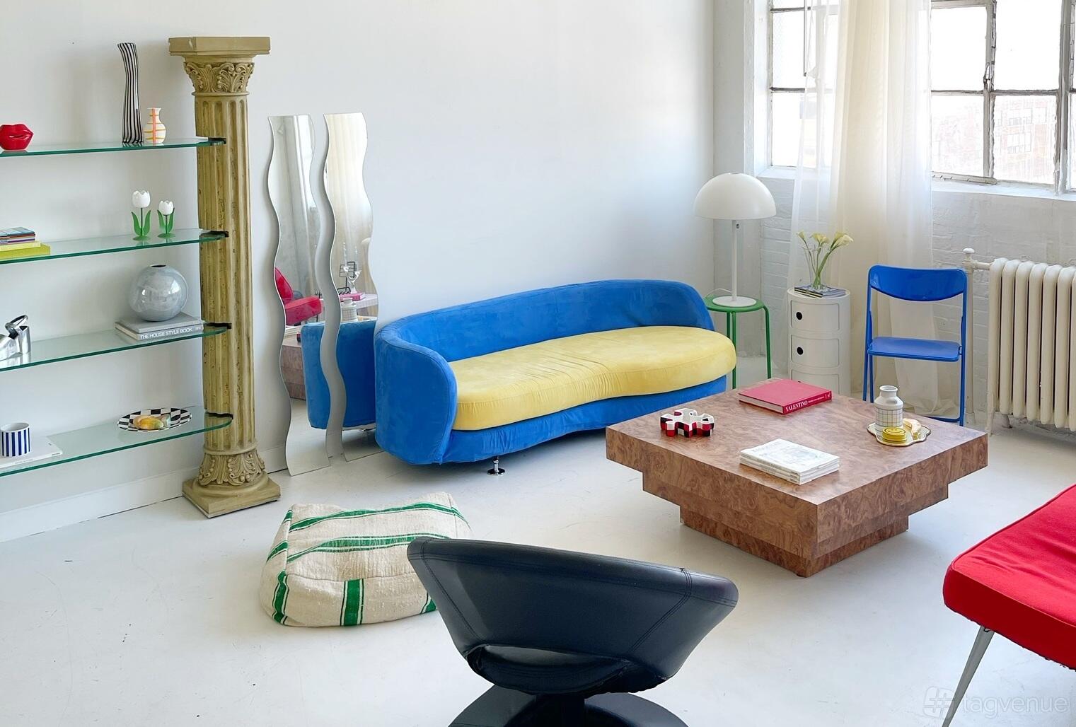 A photo studio with colorful modern furniture, large windows, and white walls at Sun and Sand Studio.
