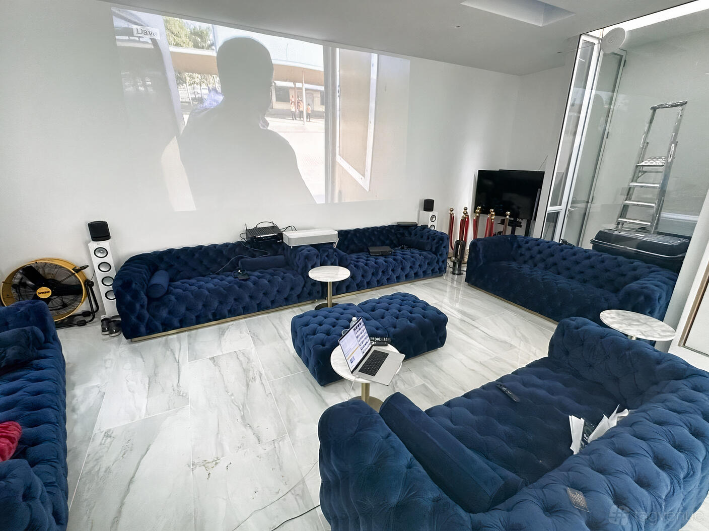 A basement studio with blue velvet sofas, marble floors, and a large projection screen at GL Basement.