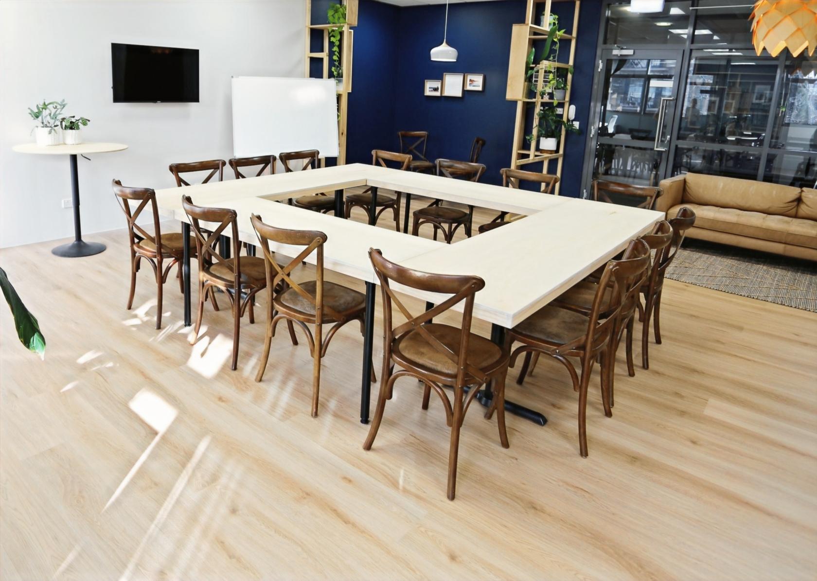 An event venue with a U-shaped table arrangement, wooden chairs, and natural light at Subi Space.