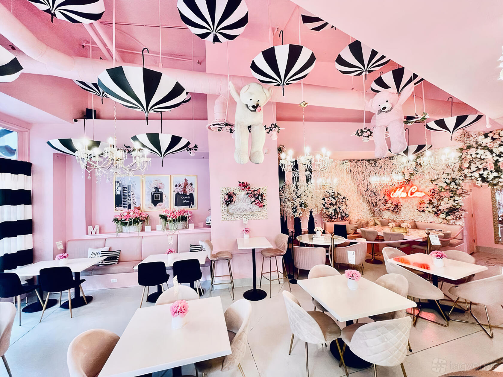 A cafe with pink decor, hanging black-and-white umbrellas, plush bears, floral arrangements, and chandeliers at Mrs. Coco Cafe.