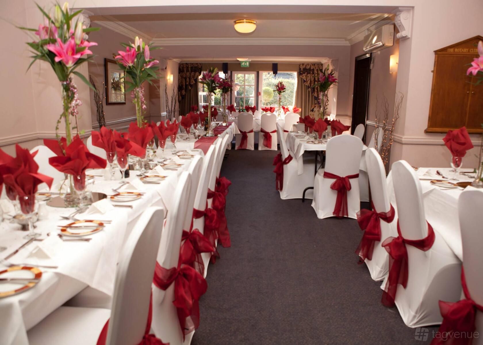An event space with banquet tables dressed in white linens and red chair sashes at Stuart House Hotel.