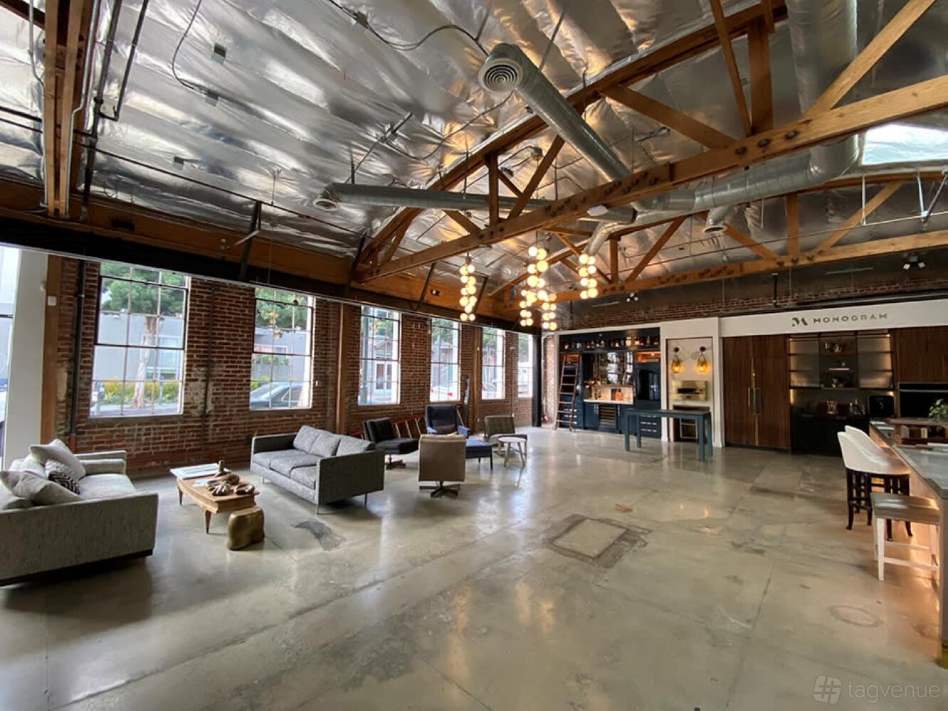 An event venue studio with exposed brick walls, large windows, and lounge seating at Cozy Stylish Chic.