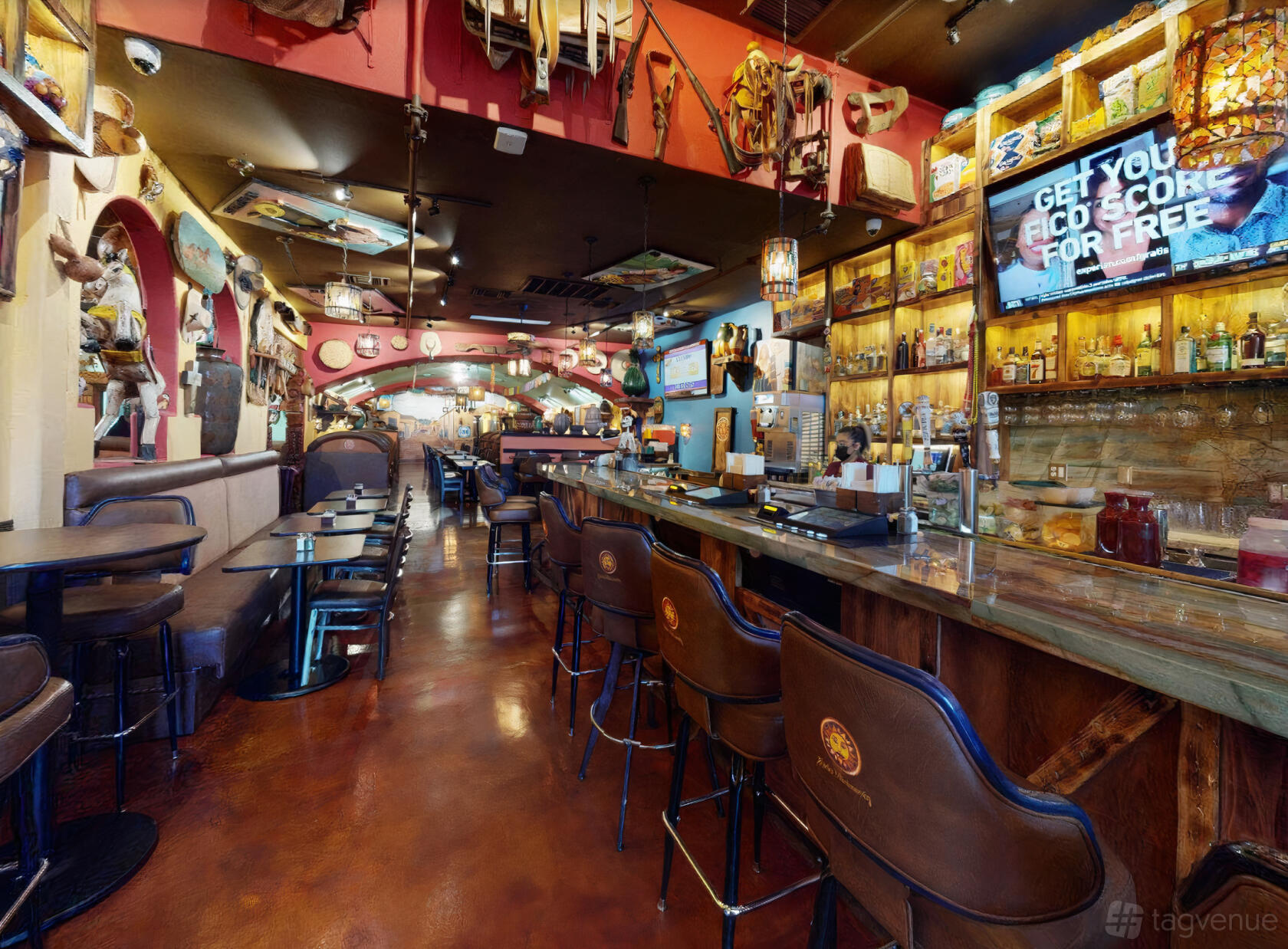 A restaurant bar with leather barstools, a long marble counter, and shelves of bottles at Lindo Michoacan Desert Inn.