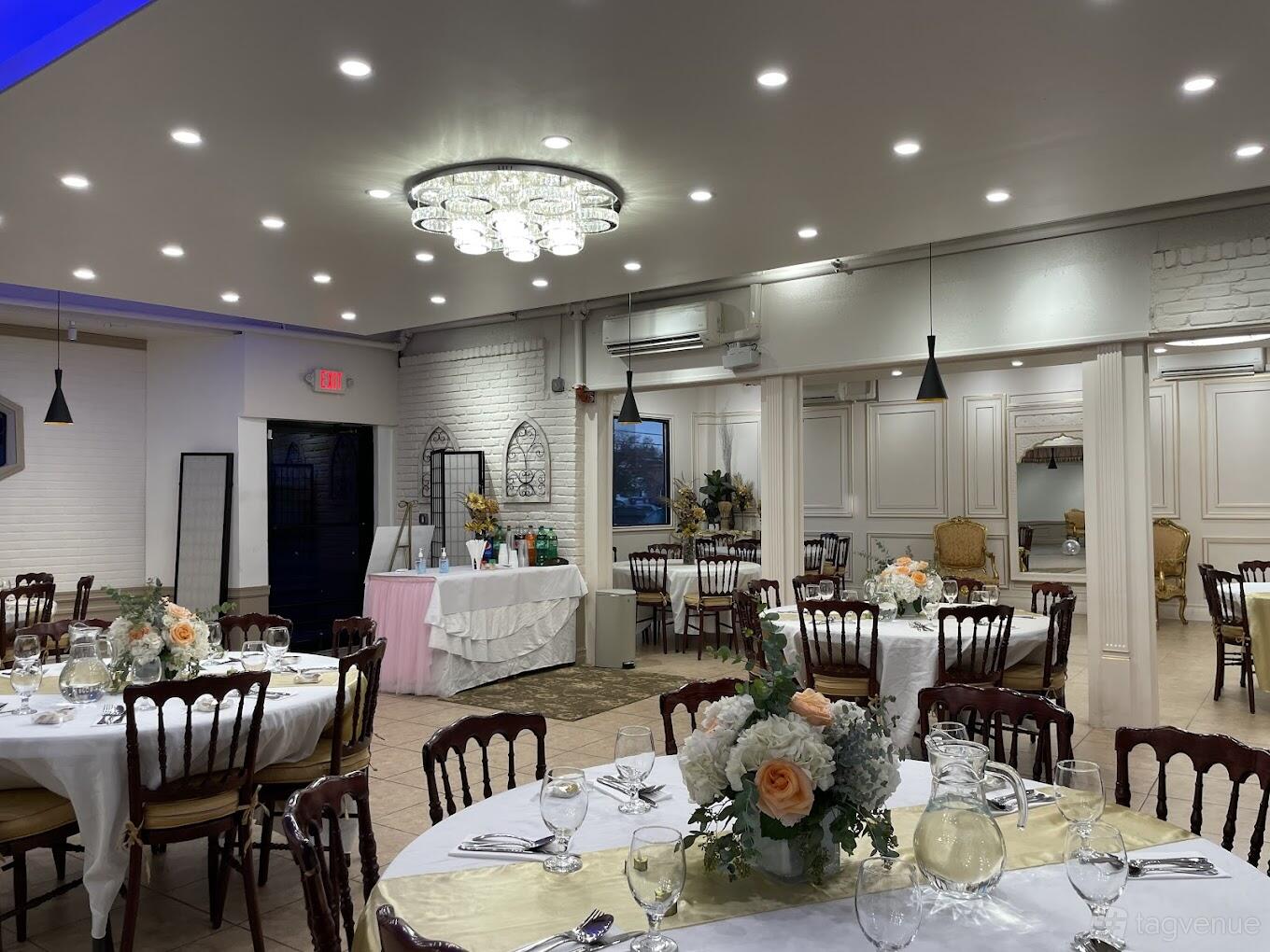 A banquet hall with round tables set with floral centerpieces, wooden chairs, and a crystal chandelier at The Event Place.