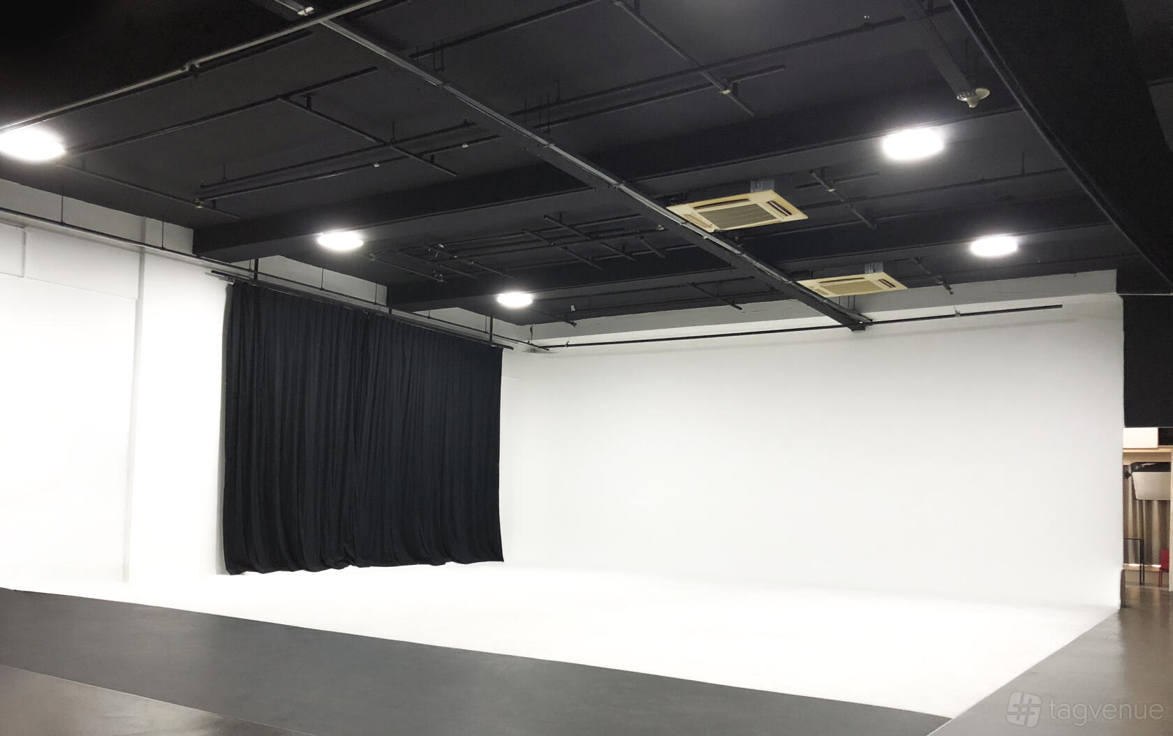 A photo studio with white cyclorama walls, black ceiling, and overhead studio lighting at Stills Network.
