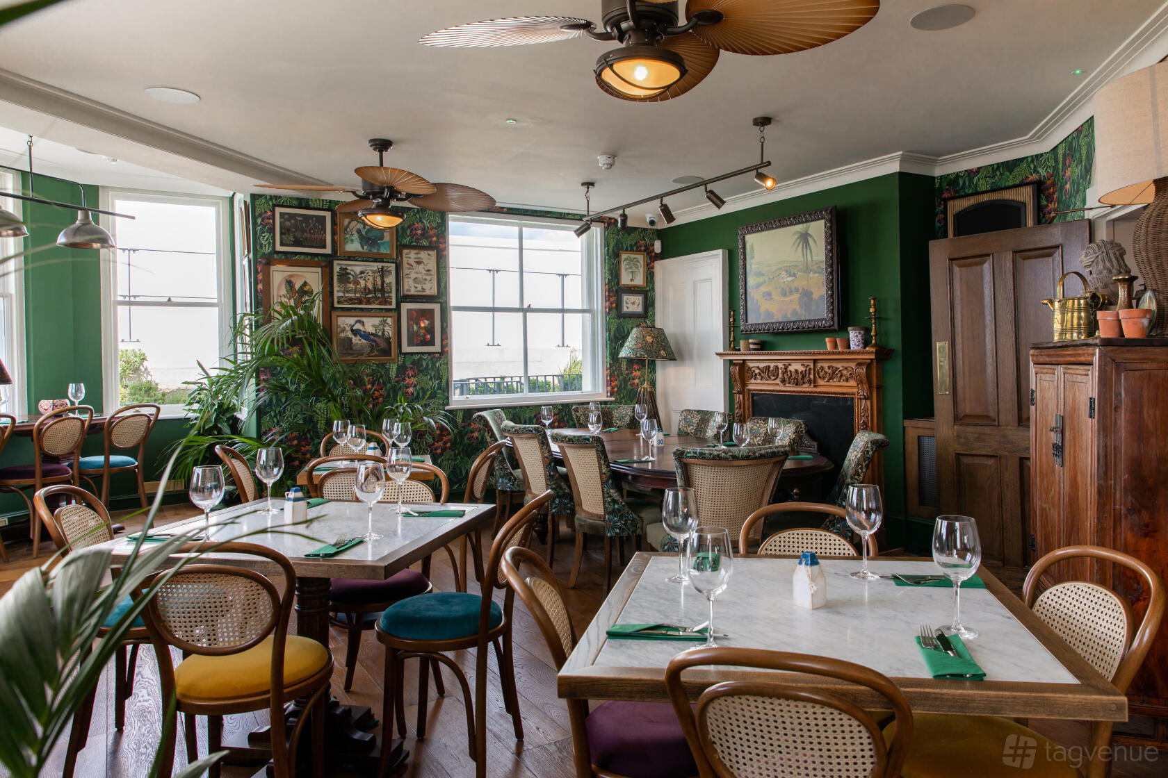 A pub with marble-top tables, cane chairs, green walls, and framed artwork at Enderby House.