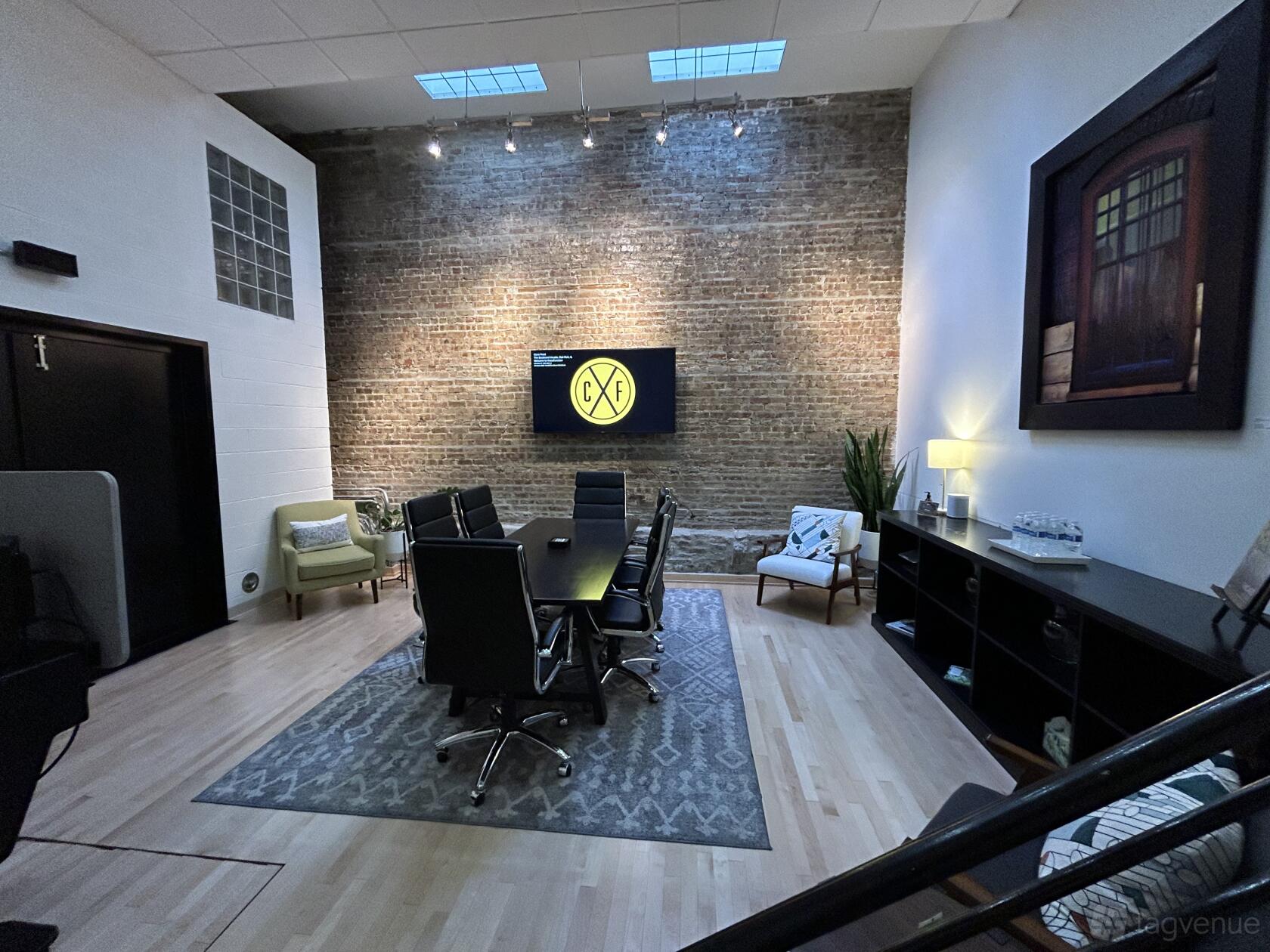 A meeting room with exposed brick wall, central conference table, and lounge seating at The Boulevard Arcade by CrossFunction.