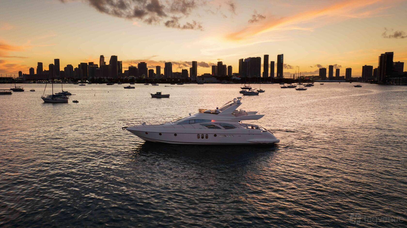 A yacht with a sleek white exterior cruising on the water at sunset near Florida Yacht Charters & Sales.