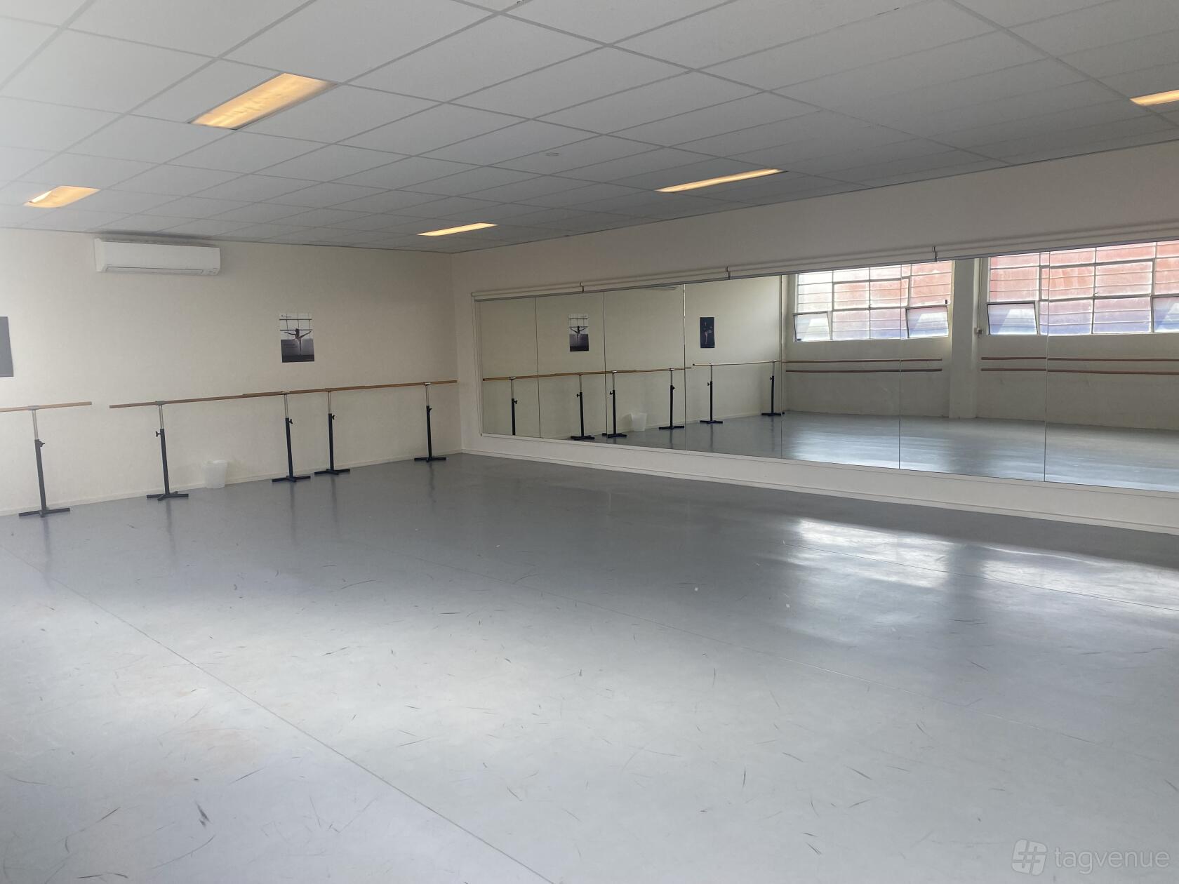 A rehearsal room with mirrored walls, ballet barres, and large windows at Rain & Lucky Academy of Dance (Preston).