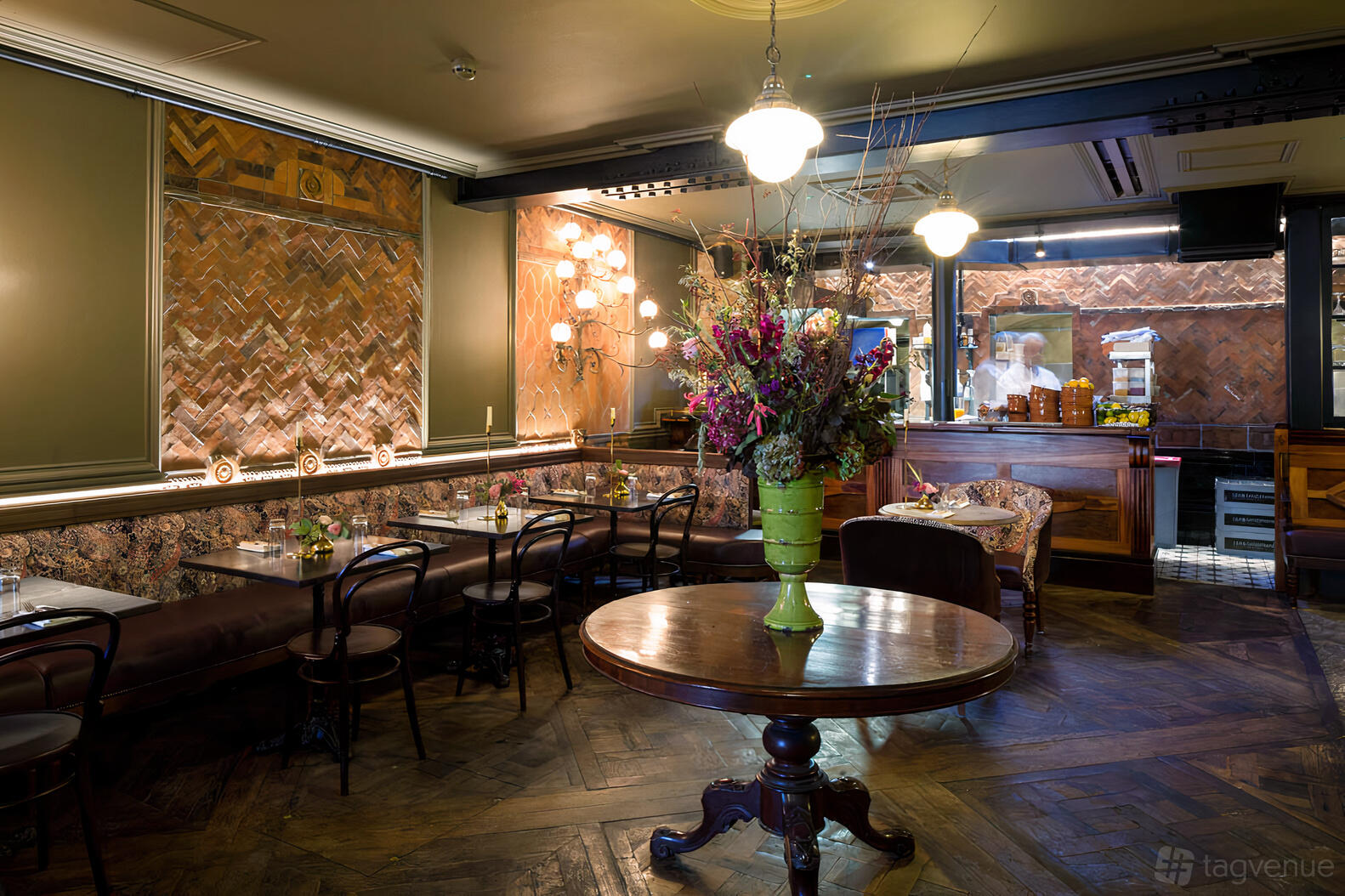 A pub interior with herringbone wood floors, exposed brick walls, and plush banquette seating at The Cleveland Arms.