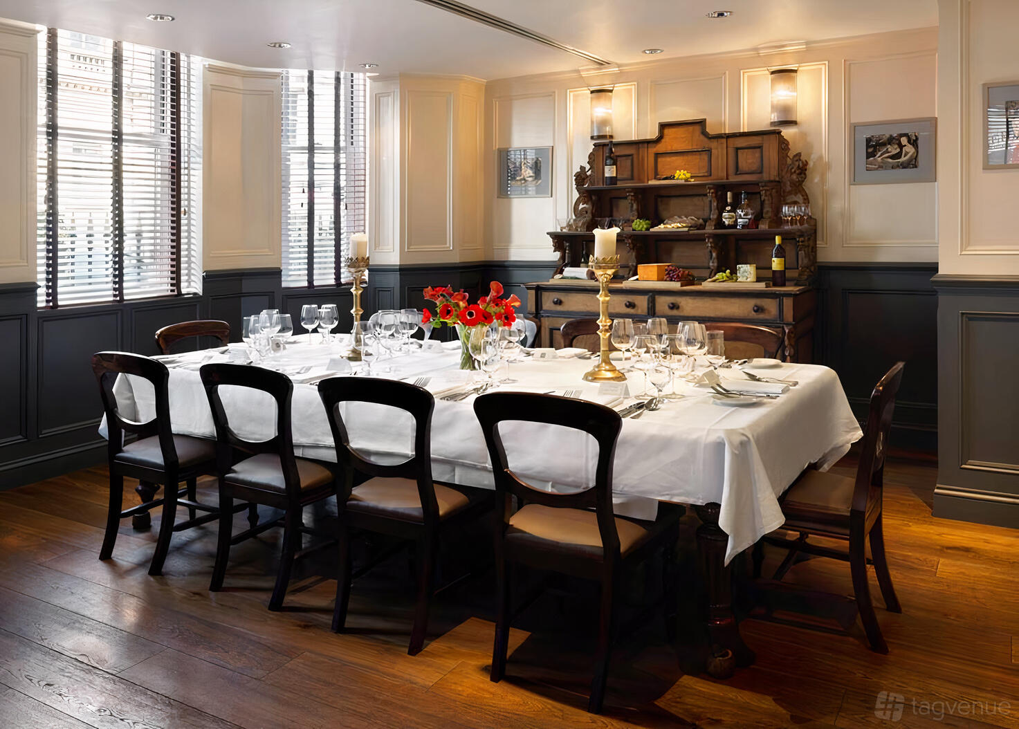 A dining room with a long table set with white linens, dark wood chairs, and vintage decor at The Mandeville Hotel.