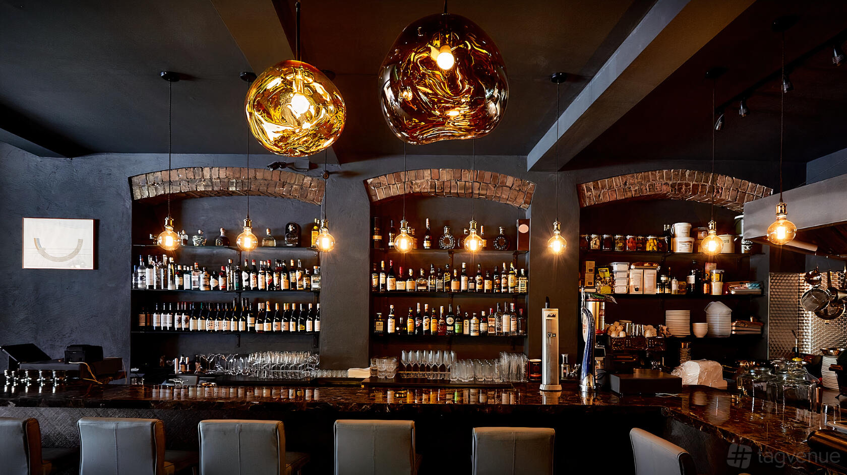 A cocktail bar with exposed brick arch shelves, hanging pendant lights, and a marble counter at belmeis.
