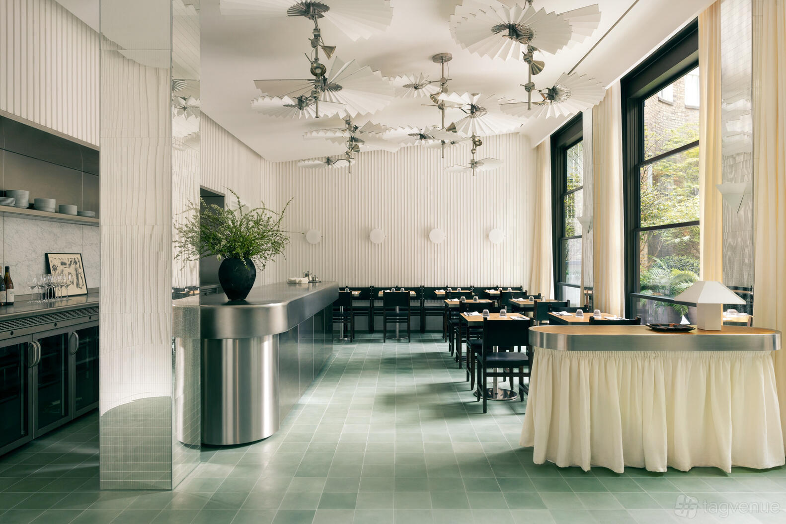 A hotel cafe with floor-to-ceiling windows, green tiled floors, and unique ceiling fans at 1 Hotel Mayfair.