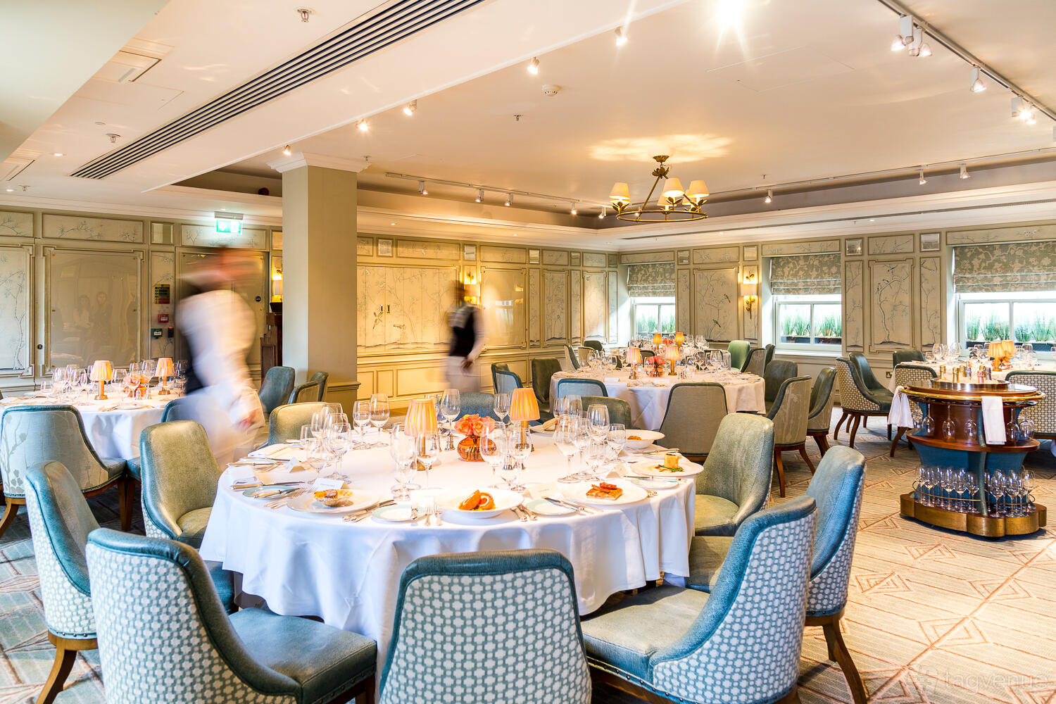 A function room with round tables set with white linens and upholstered chairs at Fortnum & Mason.