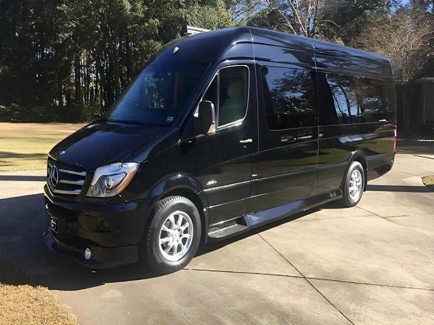 A black party bus with tinted windows, silver rims, and a Mercedes-Benz emblem at Famous Drive.