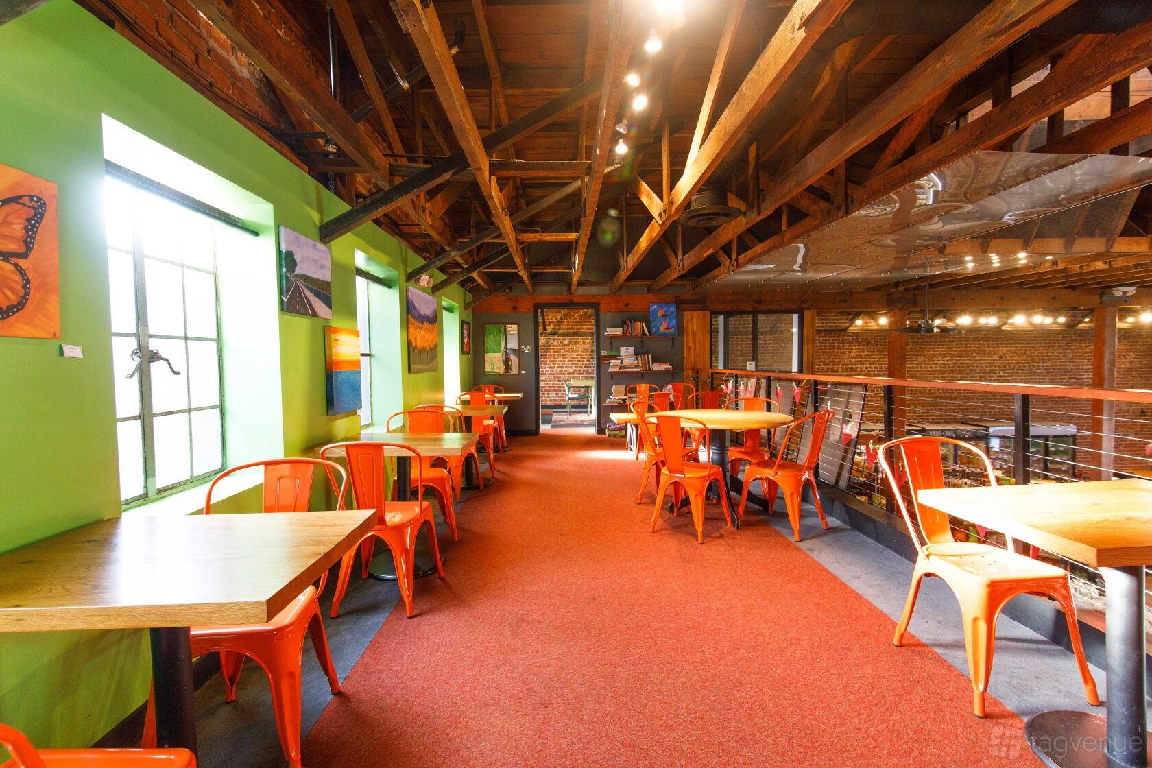 A cafe with exposed wooden beams, red chairs, and wall art at With Love Market & Cafe.