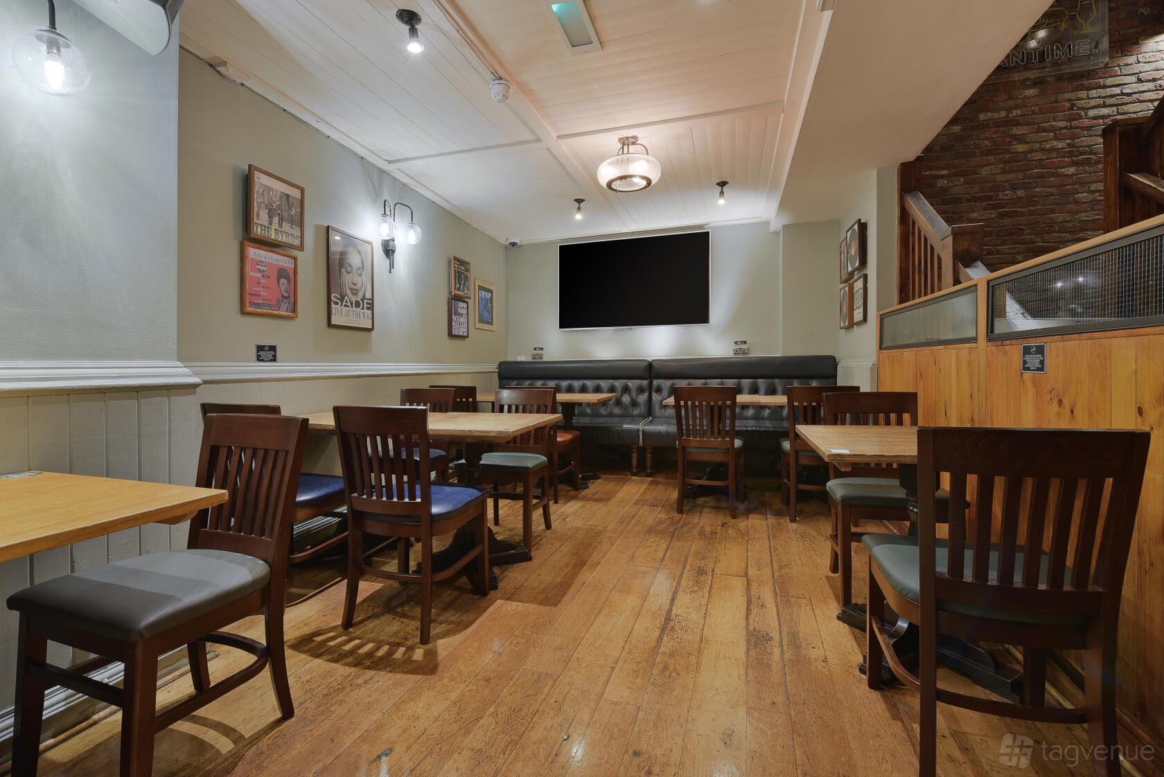 An event space in a pub with wooden floors, framed posters, and wooden tables and chairs at O'Neill's Wardour Street.