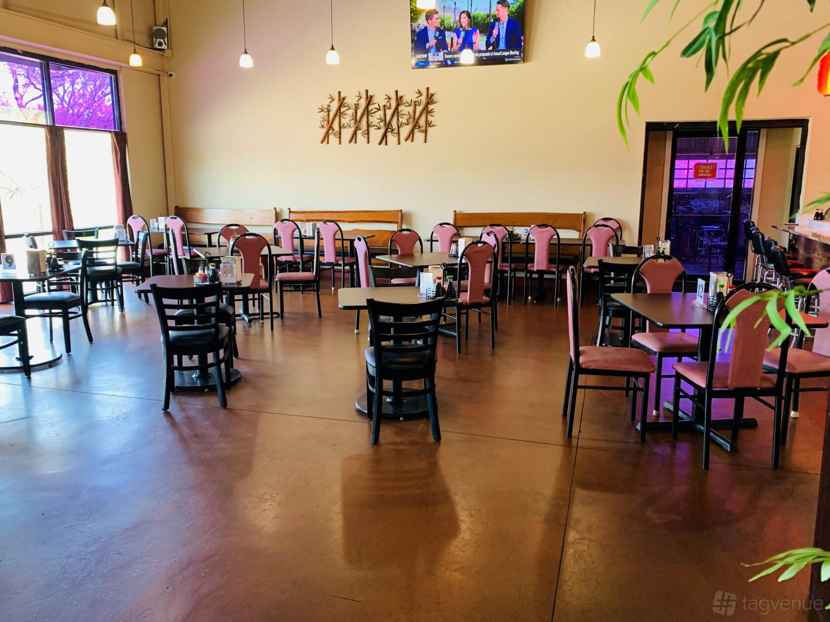 A restaurant dining area with polished concrete floors, pink cushioned chairs, and pendant lighting at Top Sushi and Grill.