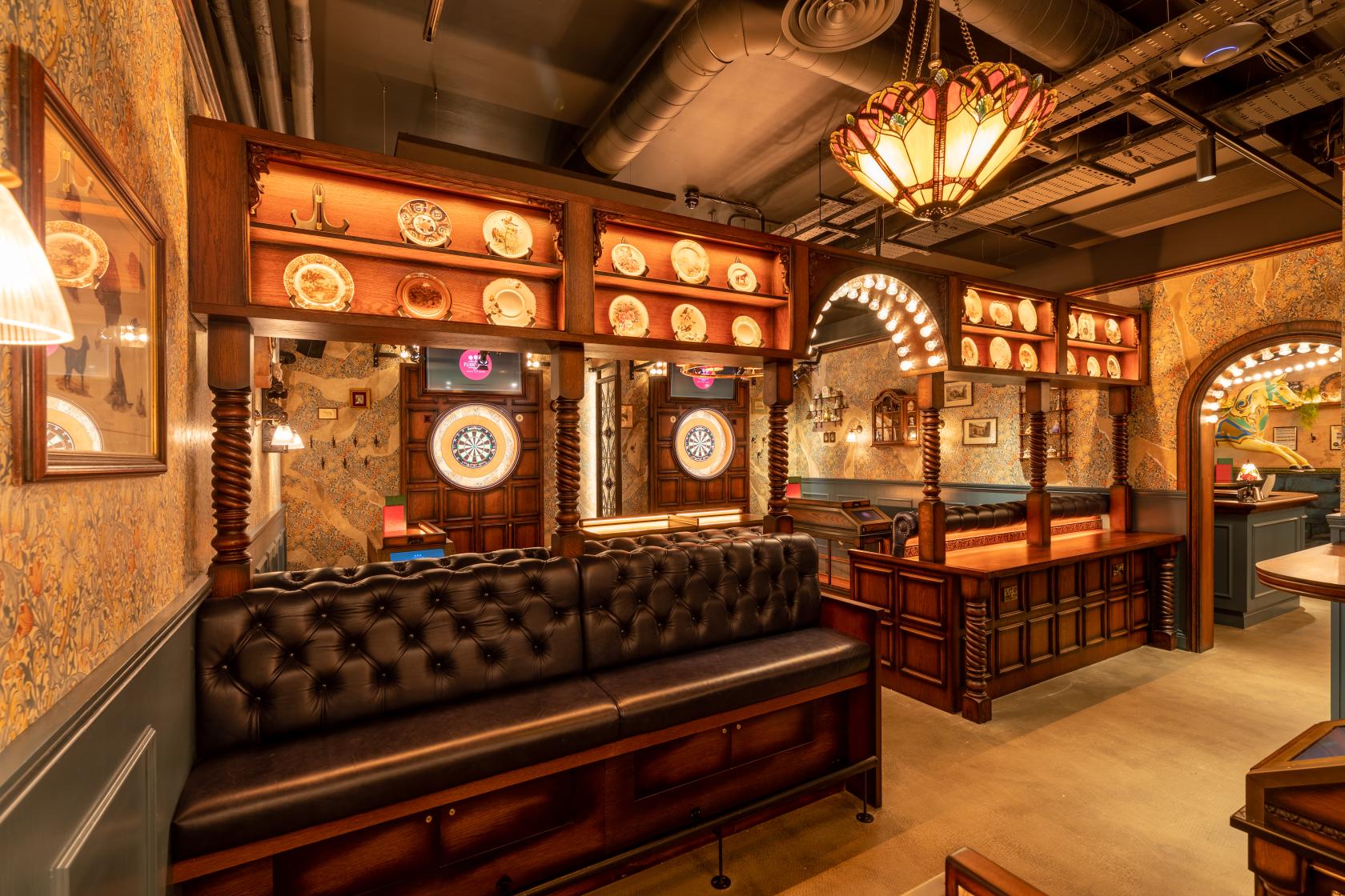 An event space with leather seating, wooden partitions, and dartboards at Flight Club Cheltenham.
