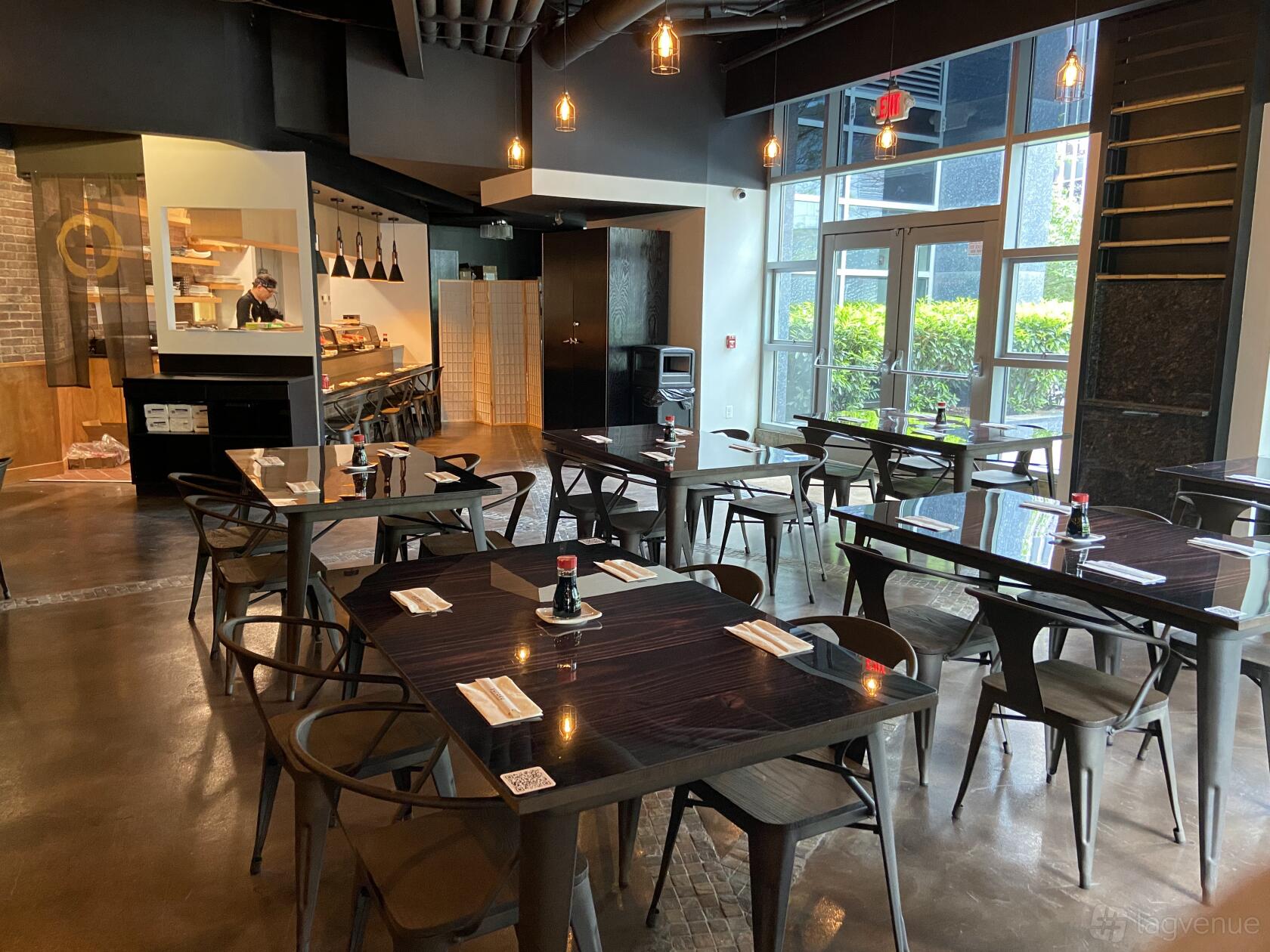An event space in a restaurant with dark wood tables, modern chairs, and natural lighting at Yuraku Japanese Restaurant.