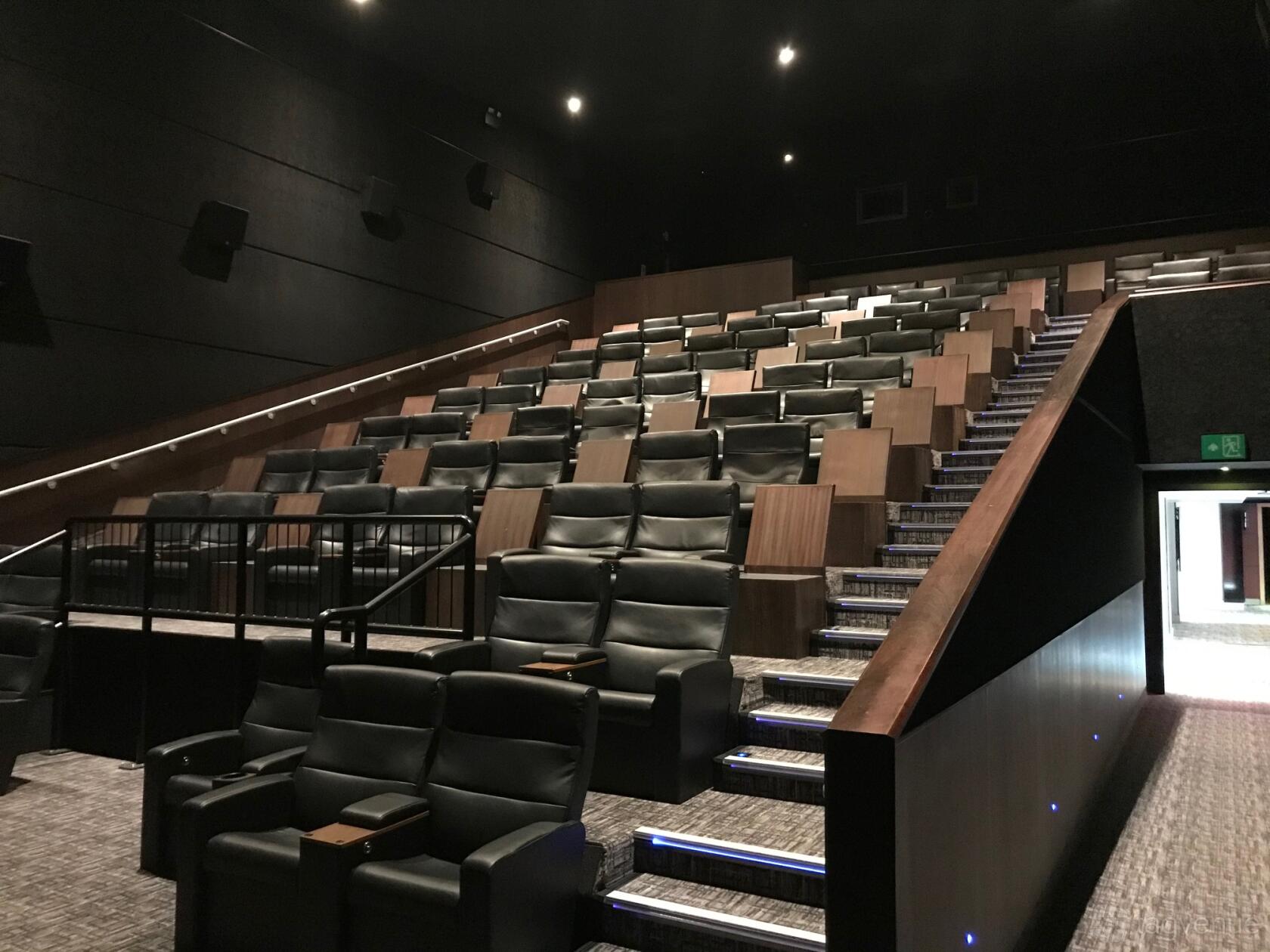 A screening room with tiered leather recliners, aisle lighting, and dark acoustic walls at Vue Westfield White City.