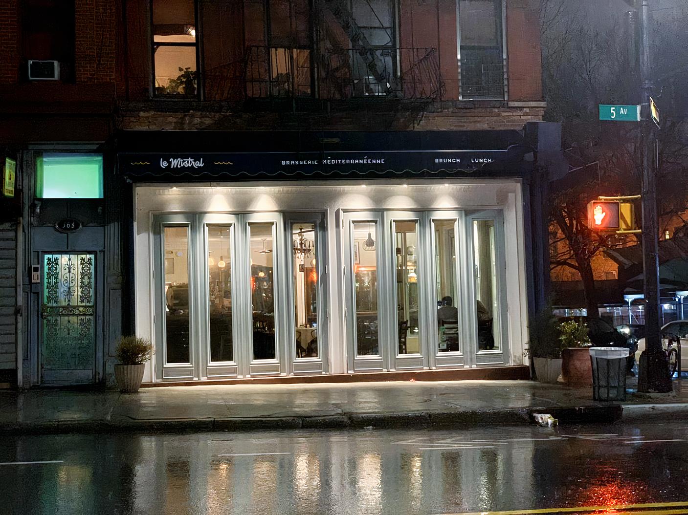 A restaurant with tall glass-paneled doors and exterior lighting at Brasserie Le Mistral