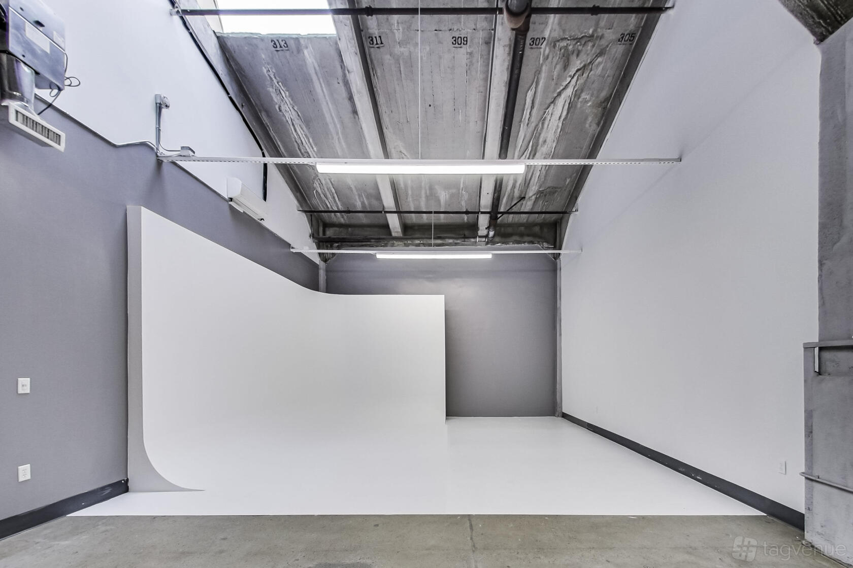 A coworking space with a white cyclorama wall and high industrial ceiling at Artthaus Studios.