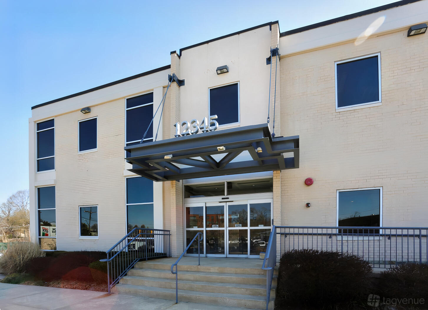 A meeting centre with a pale brick exterior, glass entry doors, and a metal awning at Perfect Office Solutions - Rockville.