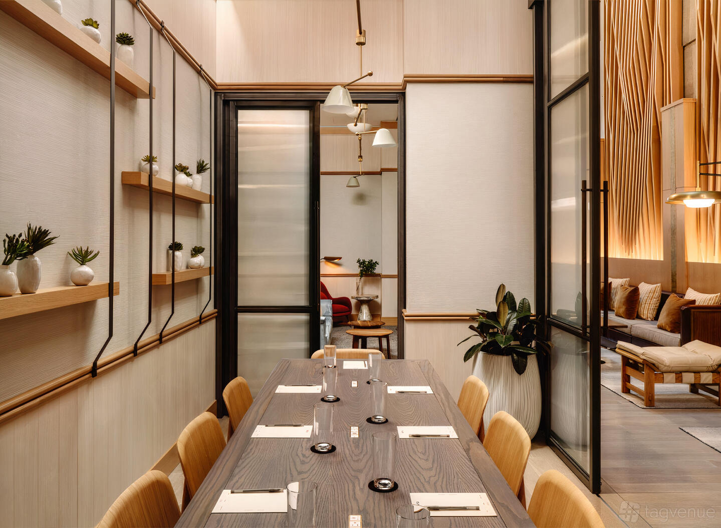 A hotel boardroom with a long wooden table, leather chairs, potted plants, and soft pendant lighting at Arlo Midtown.