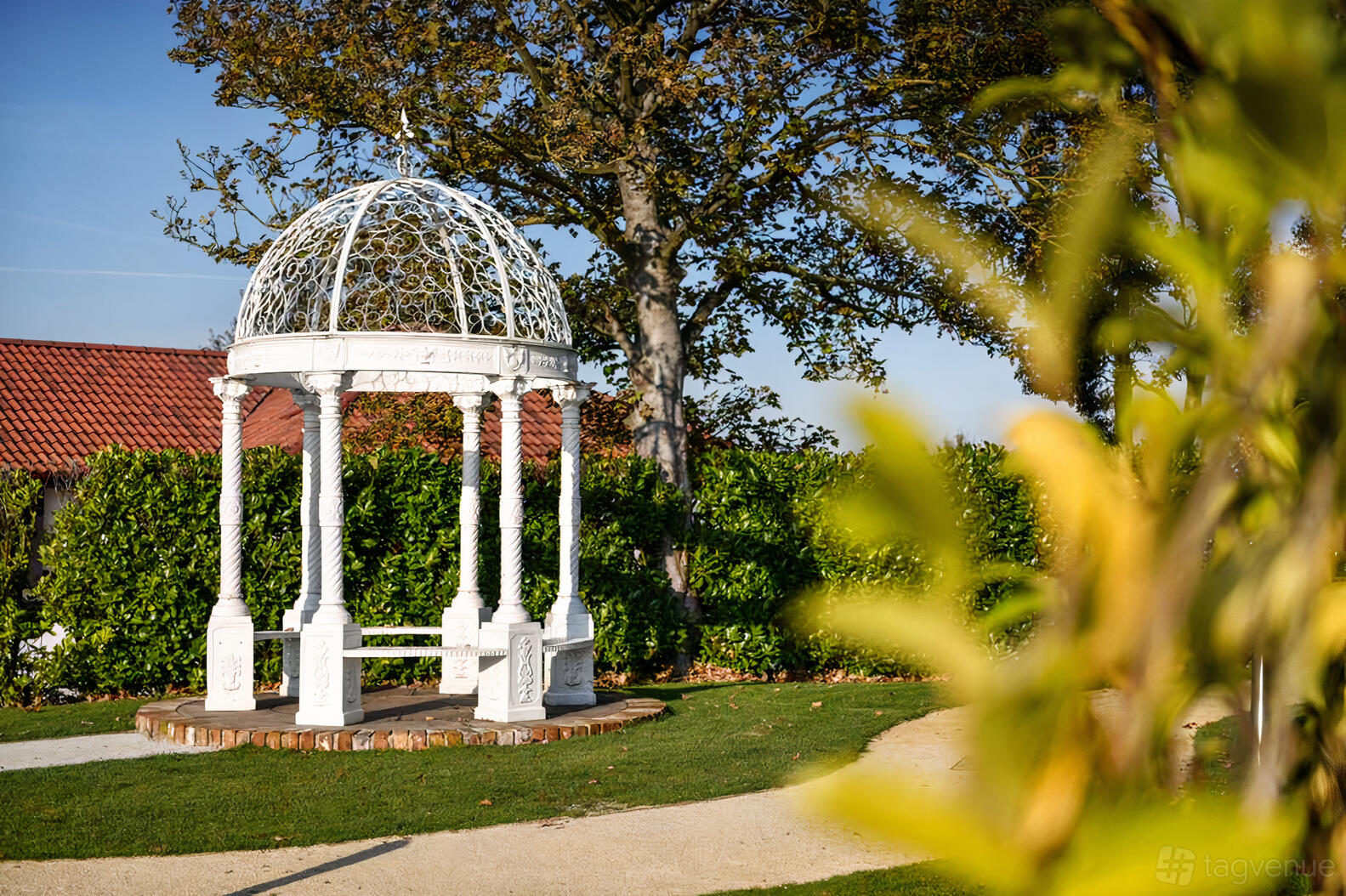 A garden area with a white wrought iron gazebo surrounded by greenery at The Nottinghamshire Golf & Country Club.