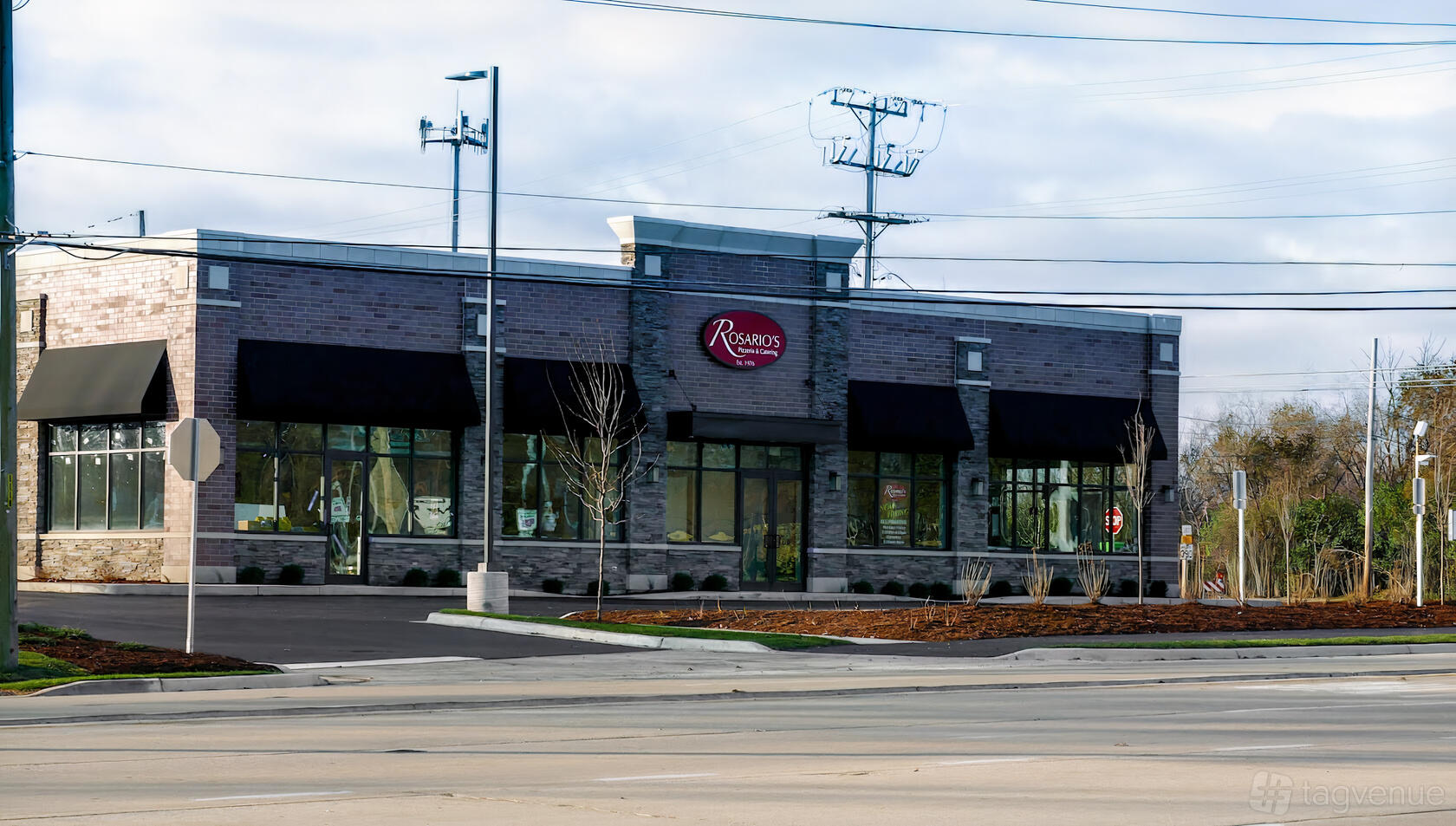 A restaurant with large windows, brick facade, black awnings, and street-facing entrance at Rosario's Pizzeria & Catering.