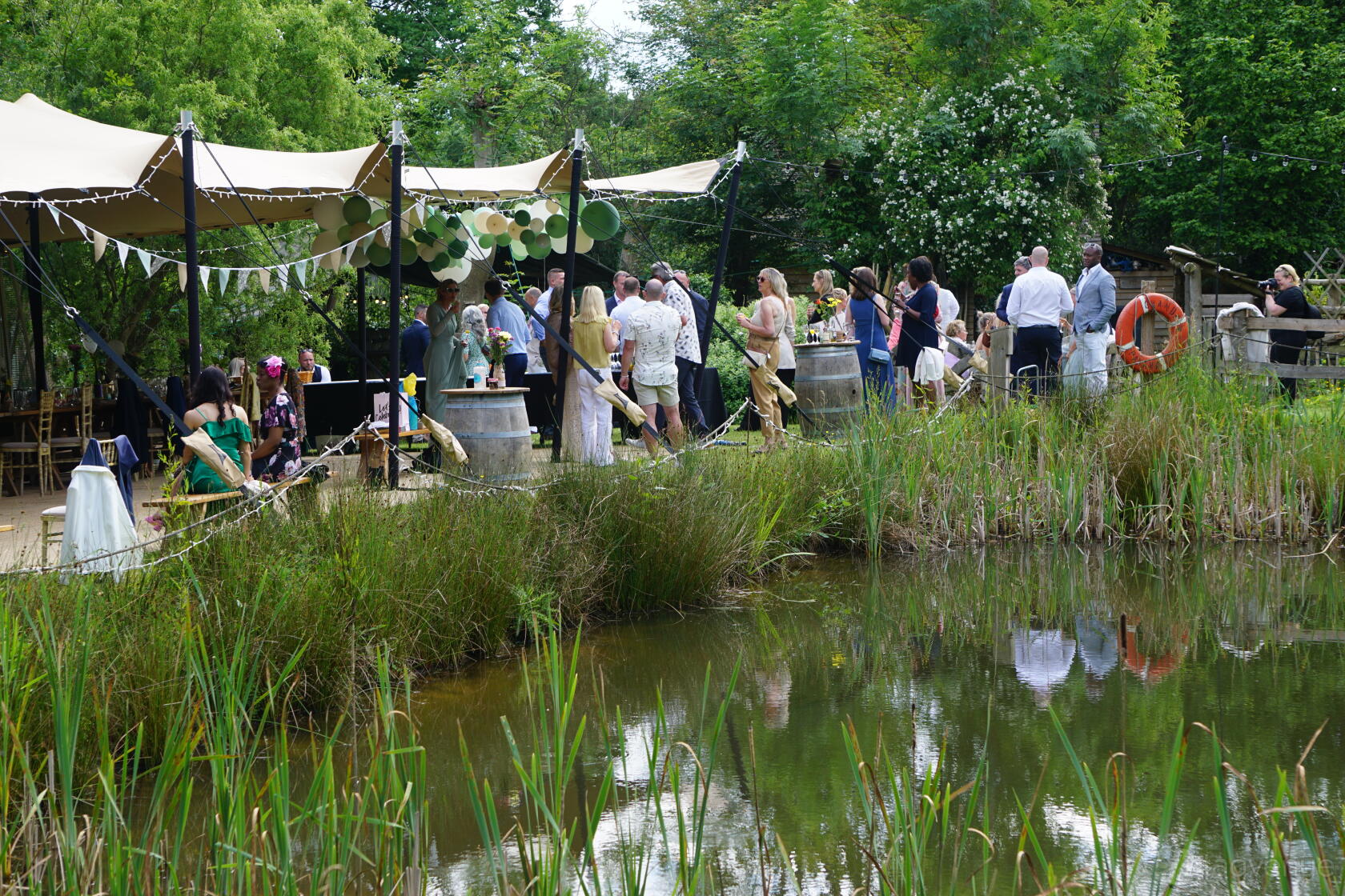 A country house with an open-air tented pavilion beside a pond and surrounded by lush greenery at Forest Garden Shovelstrode Ltd.