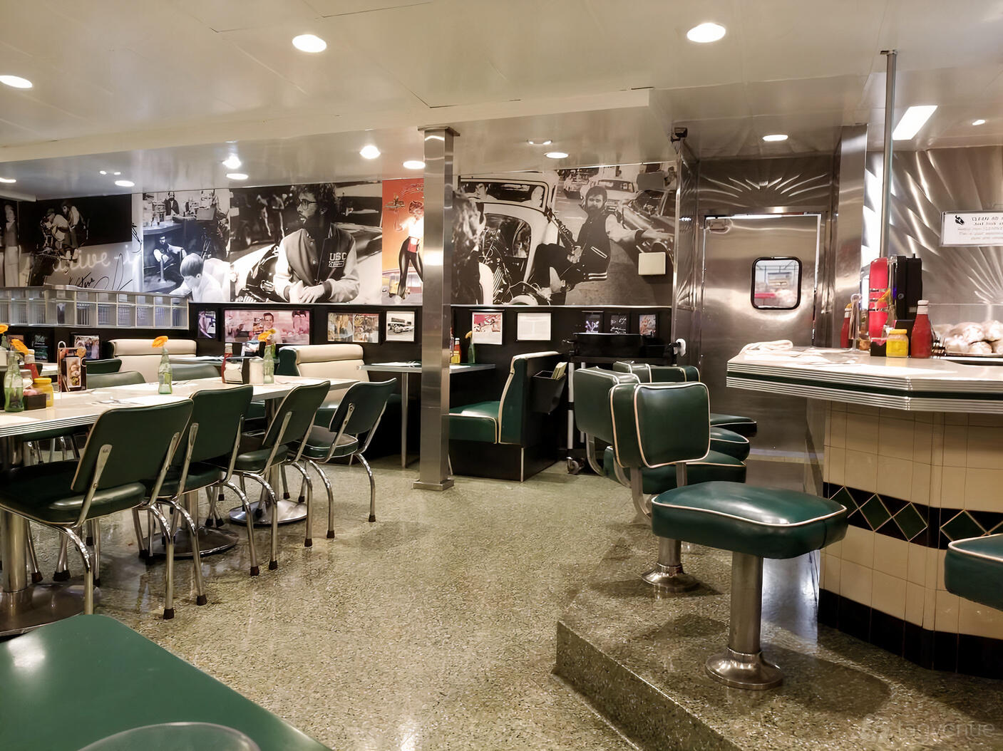 A retro restaurant with green vinyl booths, chrome accents, and vintage wall photos at Mel's Drive-In Geary Boulevard.