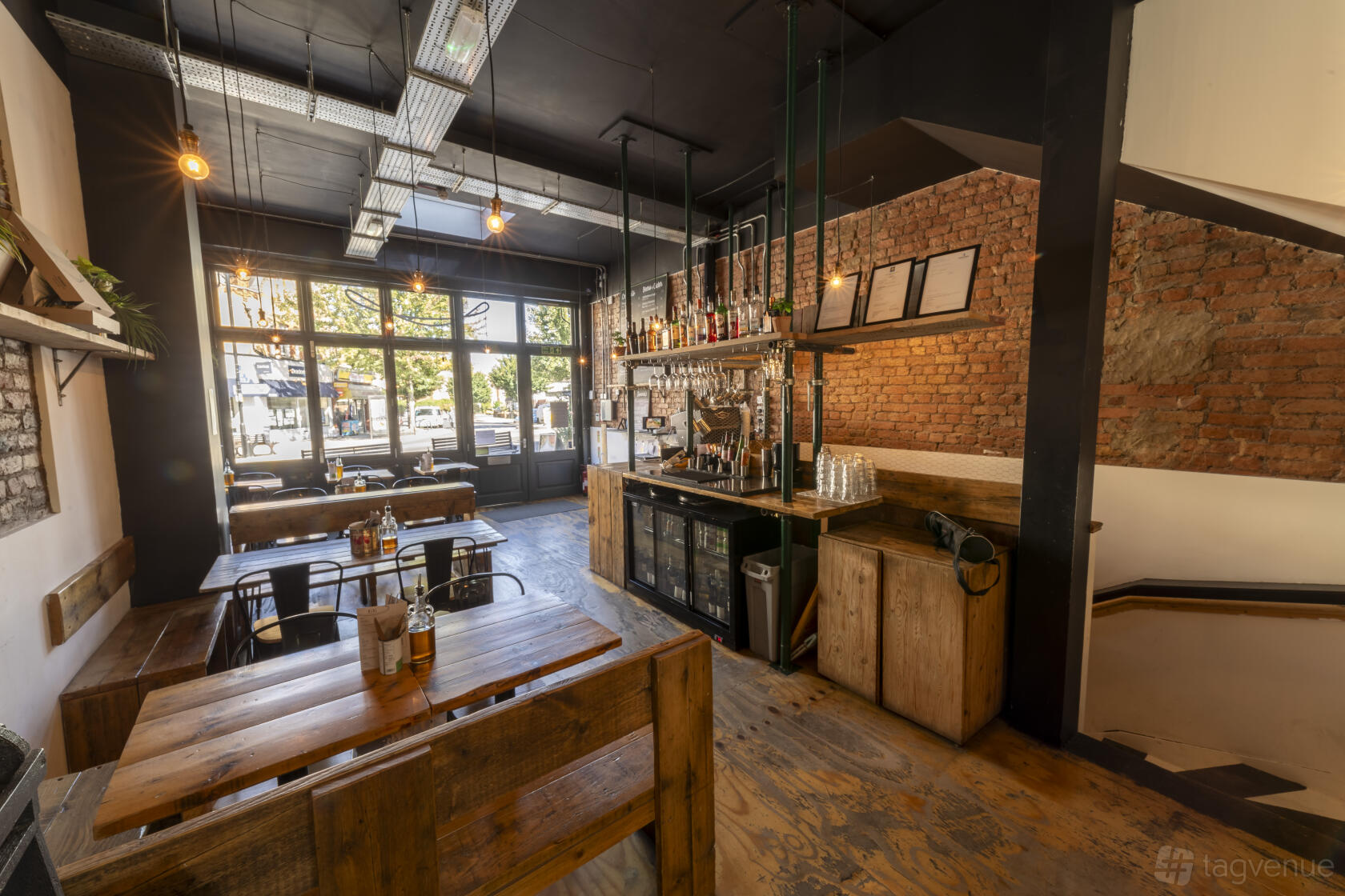 A restaurant with exposed brick walls, wooden tables, and large front windows at Mamma Dough Ladywell.