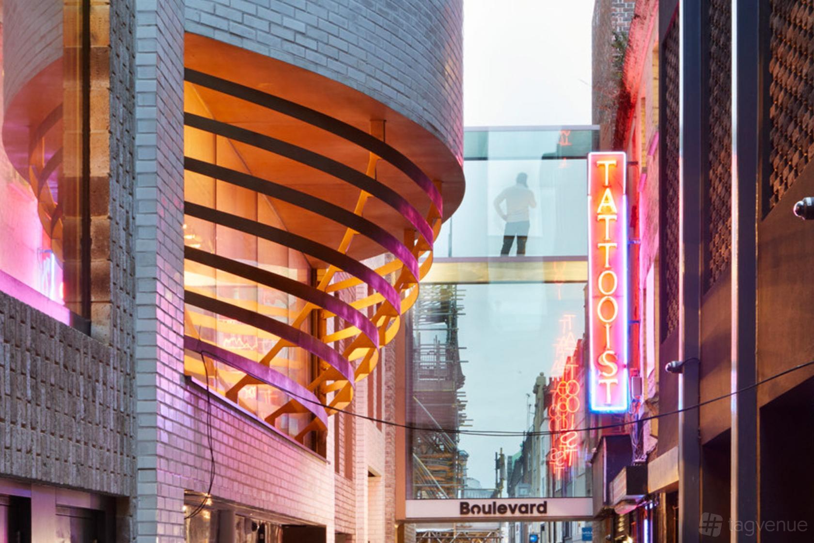 A versatile event space with neon signage, curved architectural details, and a glass walkway at Underbelly Boulevard.