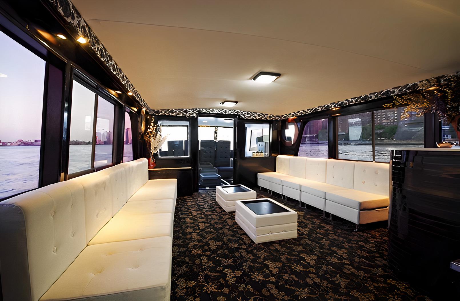 A boat lounge with large windows, white tufted sofas, patterned carpet, and low glass tables at East 23rd Street Sky Port Marina.