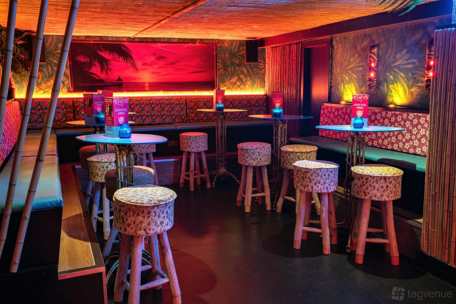 A tropical bar with bamboo stools, patterned cushions, and island-themed decor at Tiki Hideaway Manchester.