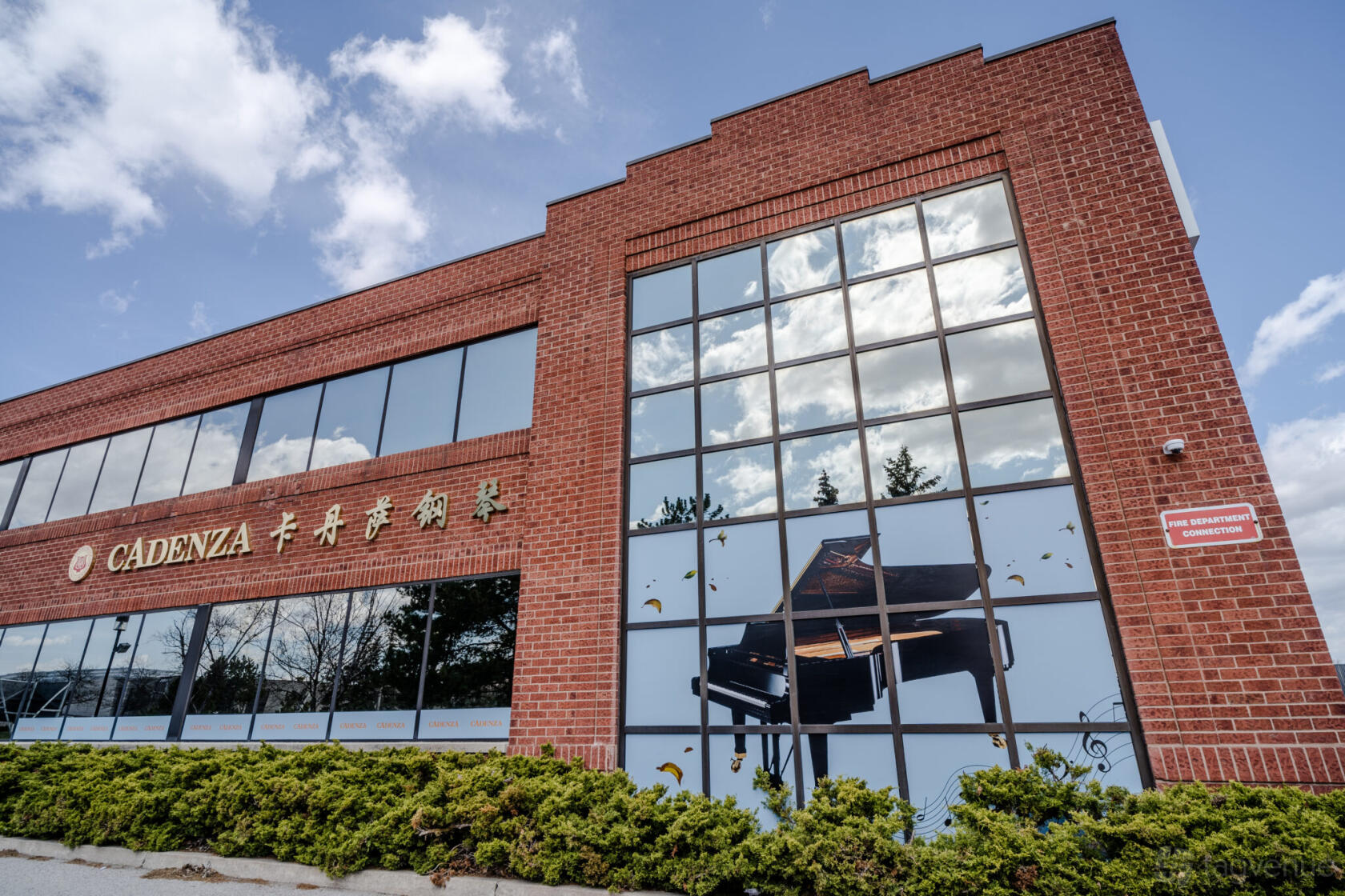 A dance studio exterior with large glass windows and a mural of a grand piano at Cadenza pianos.