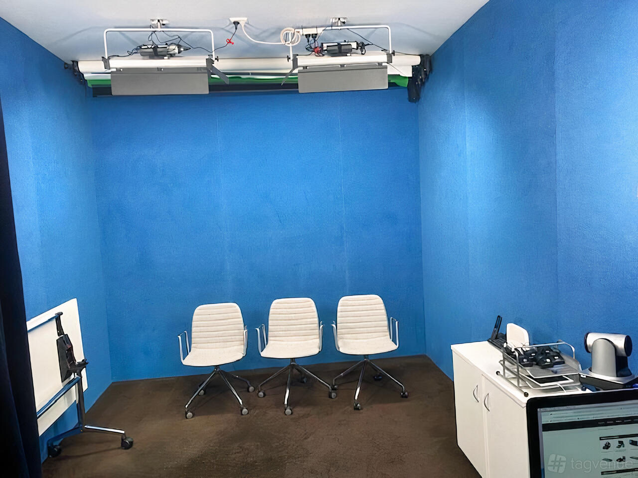 A recording room with blue acoustic walls, three white office chairs, and ceiling-mounted lights at Studio 2 Potts Point.