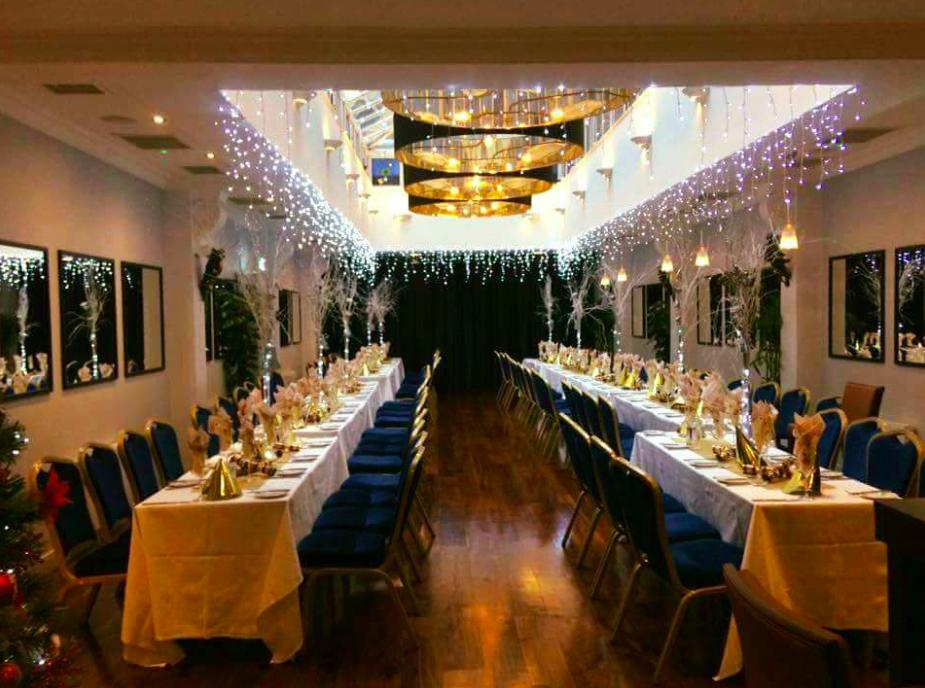 An event space with long banquet tables, festive string lights, and blue chairs at Toast