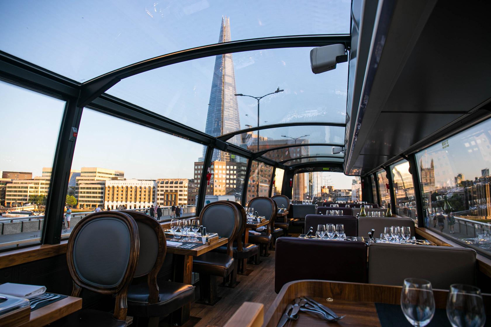 A glass-roofed restaurant with wood tables, set dining places, and city views at BUSTRONOME.