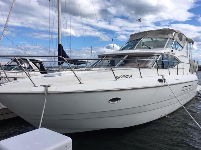 A large white yacht with upper and lower decks docked beside other boats at Toronto Yachts.