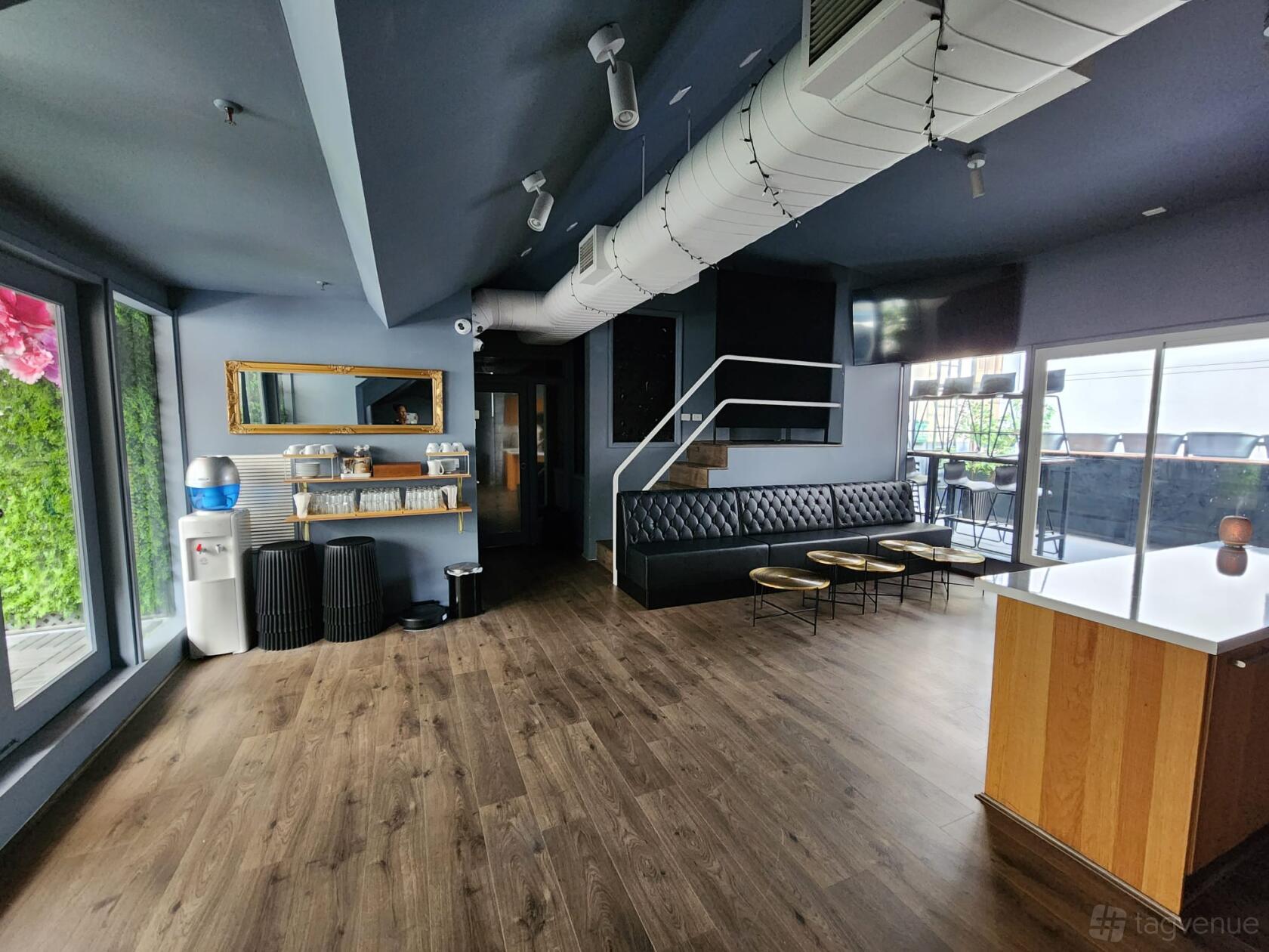 An event loft with wood floors, black tufted bench seating, gold accent tables, and a marble bar at Loft on George.