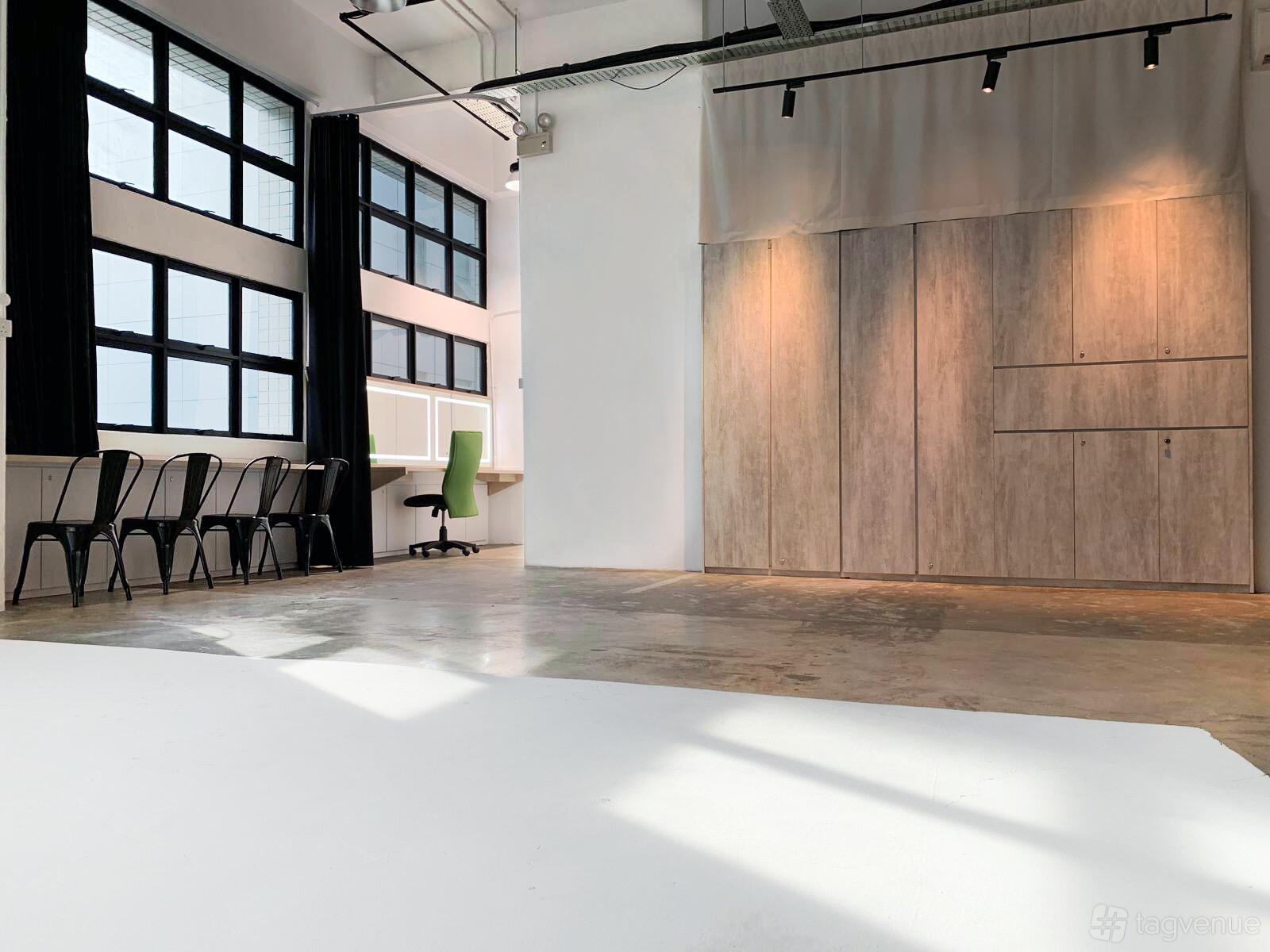 A photo studio with high ceilings, large windows, concrete floors, and wood panel dividers at Studio Rental House.