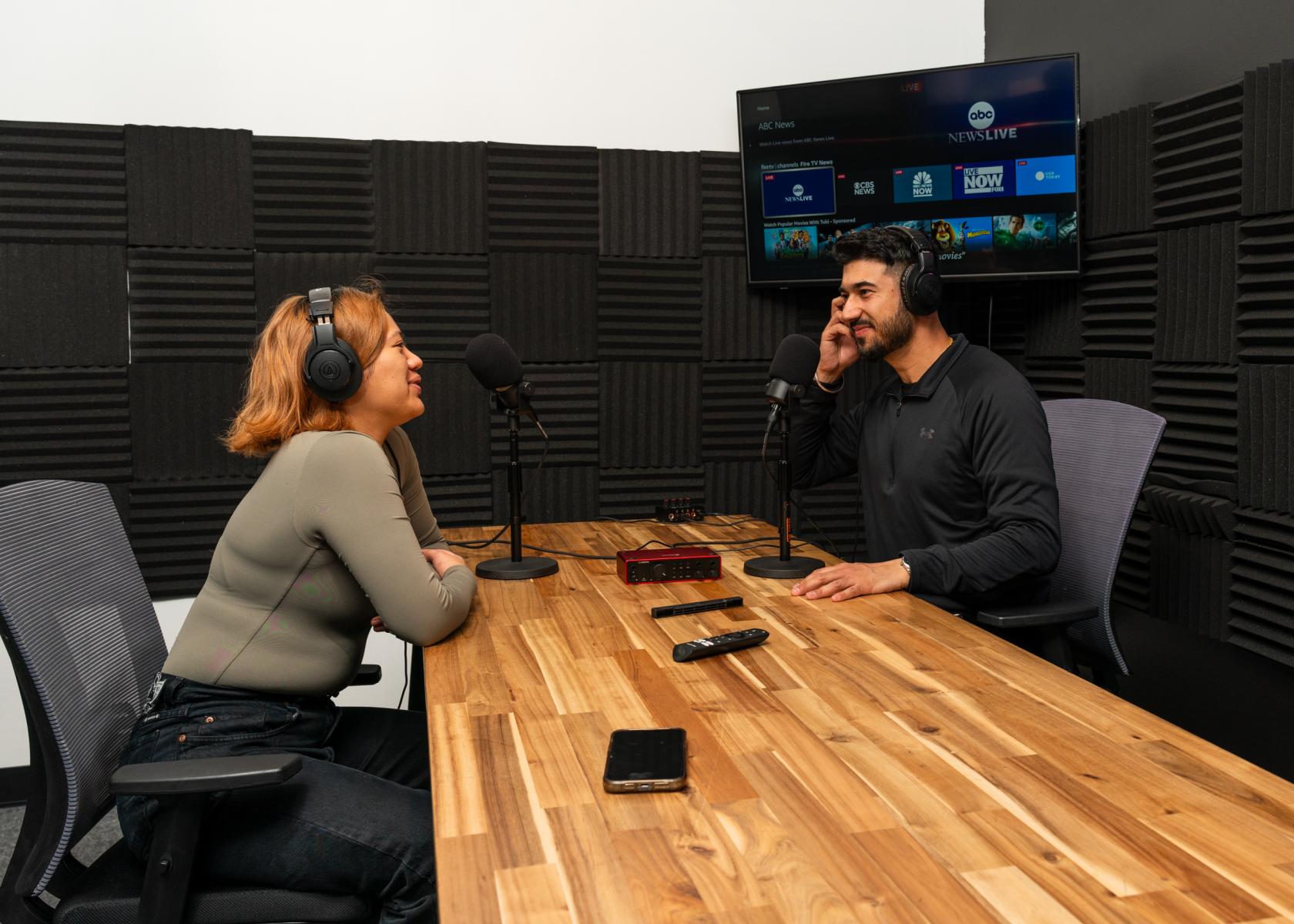 A coworking space with soundproof walls, a wooden podcast table, studio microphones, and headphones at Werqwise San Francisco.